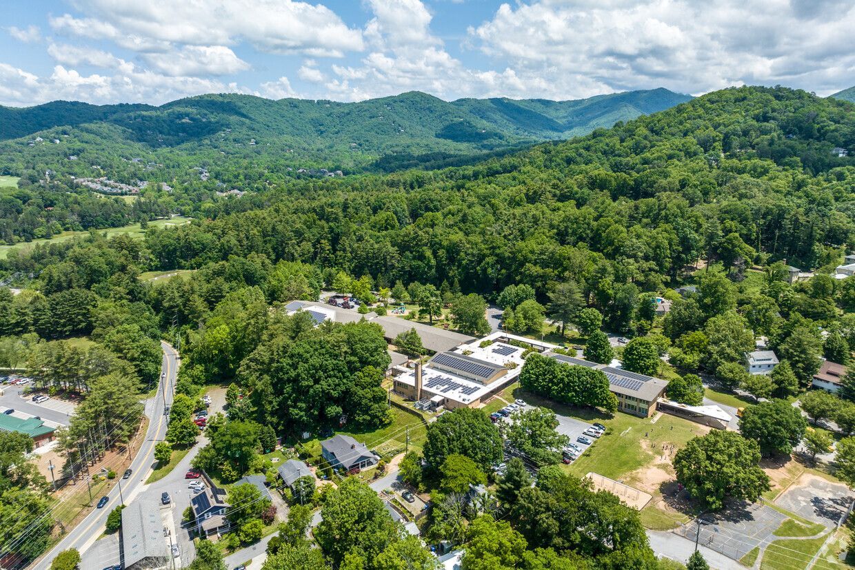 An aerial view of a residential area surrounded by trees and mountains.