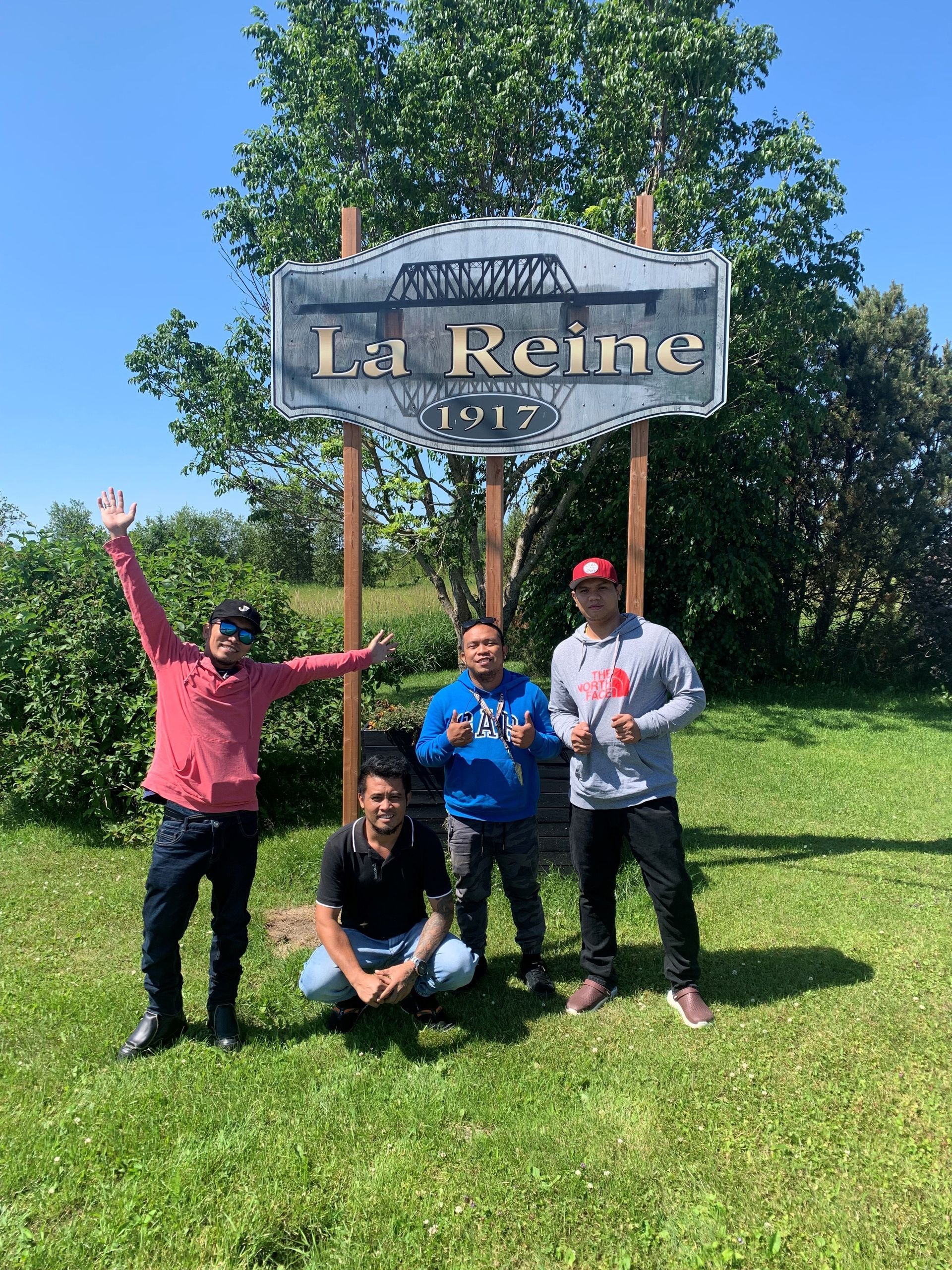 A group of men are posing for a picture in front of a la reine sign.