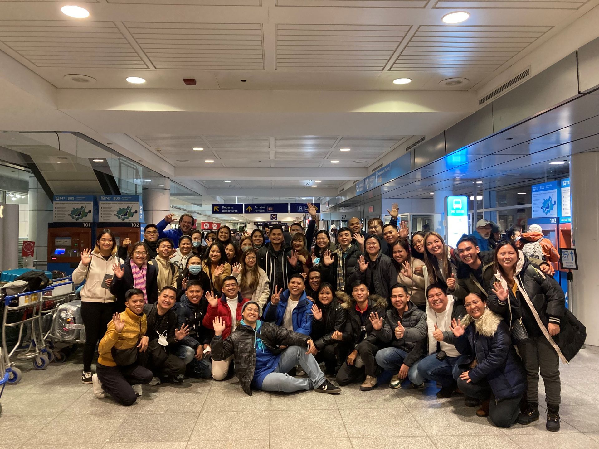 A large group of people are posing for a picture in an airport.