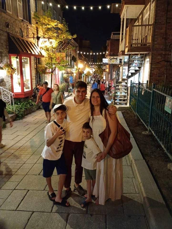 A family is posing for a picture on a sidewalk at night.