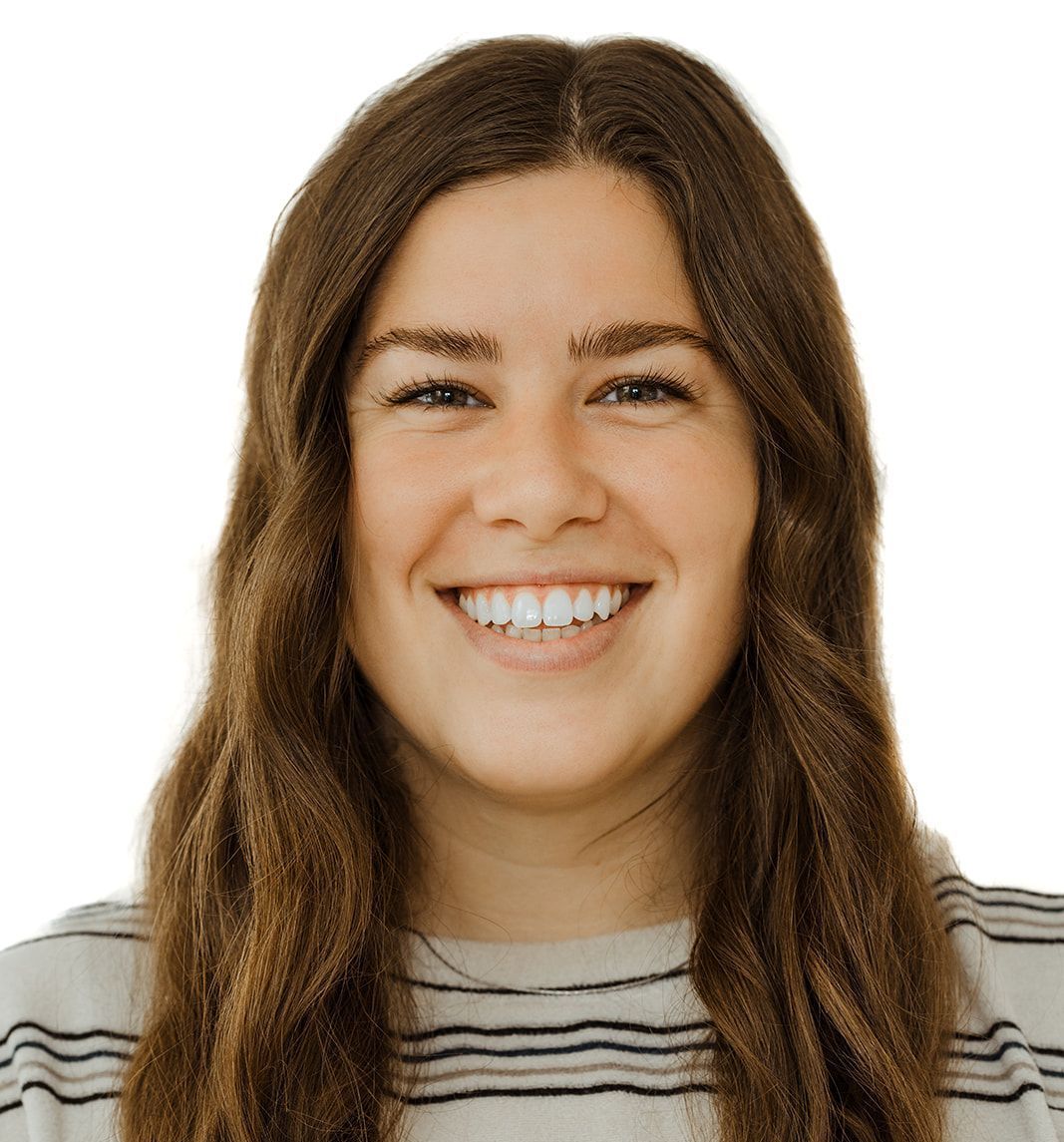 A woman with long brown hair is smiling and wearing a striped shirt.