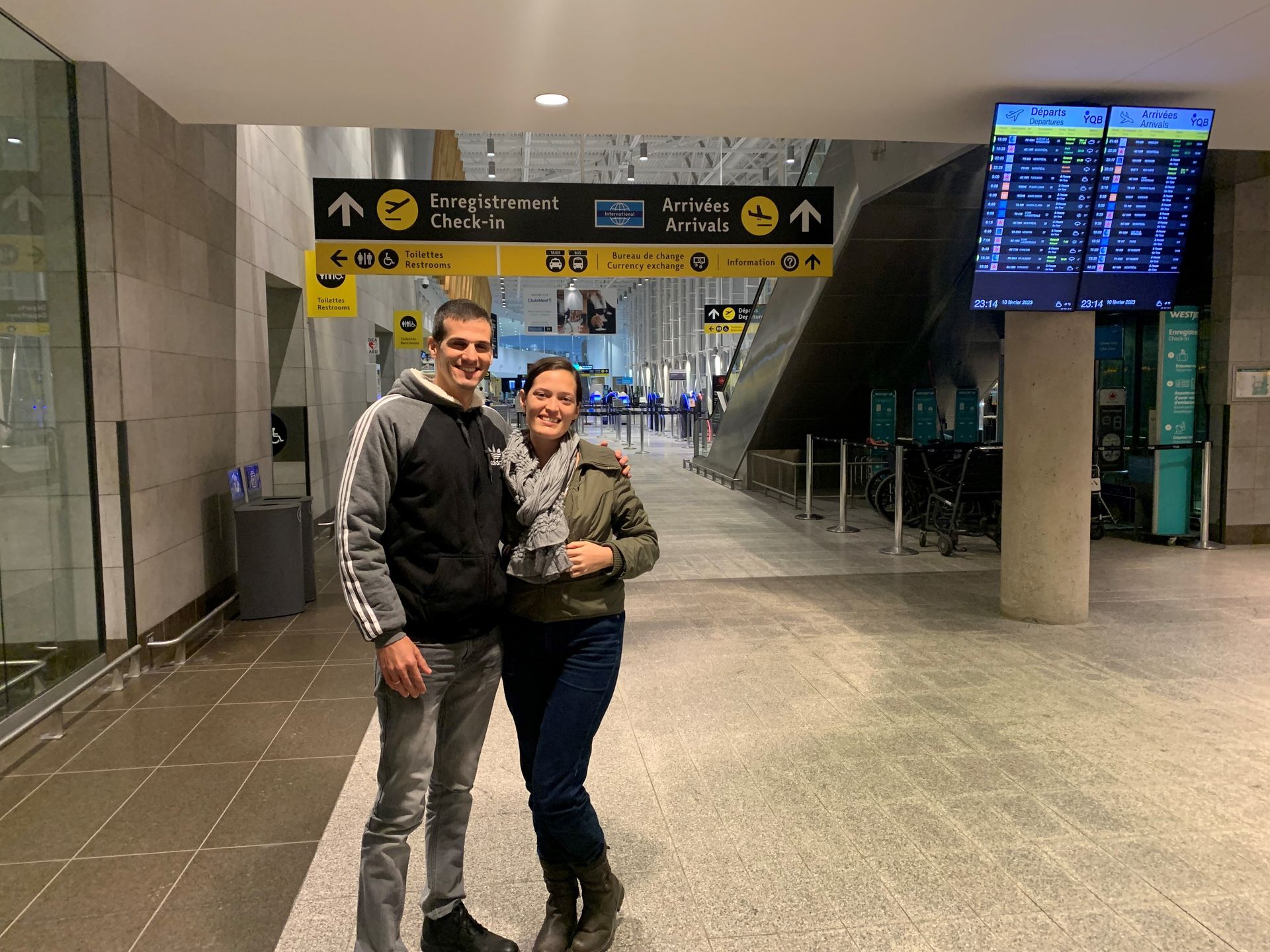 A man and a woman are standing next to each other in an airport.