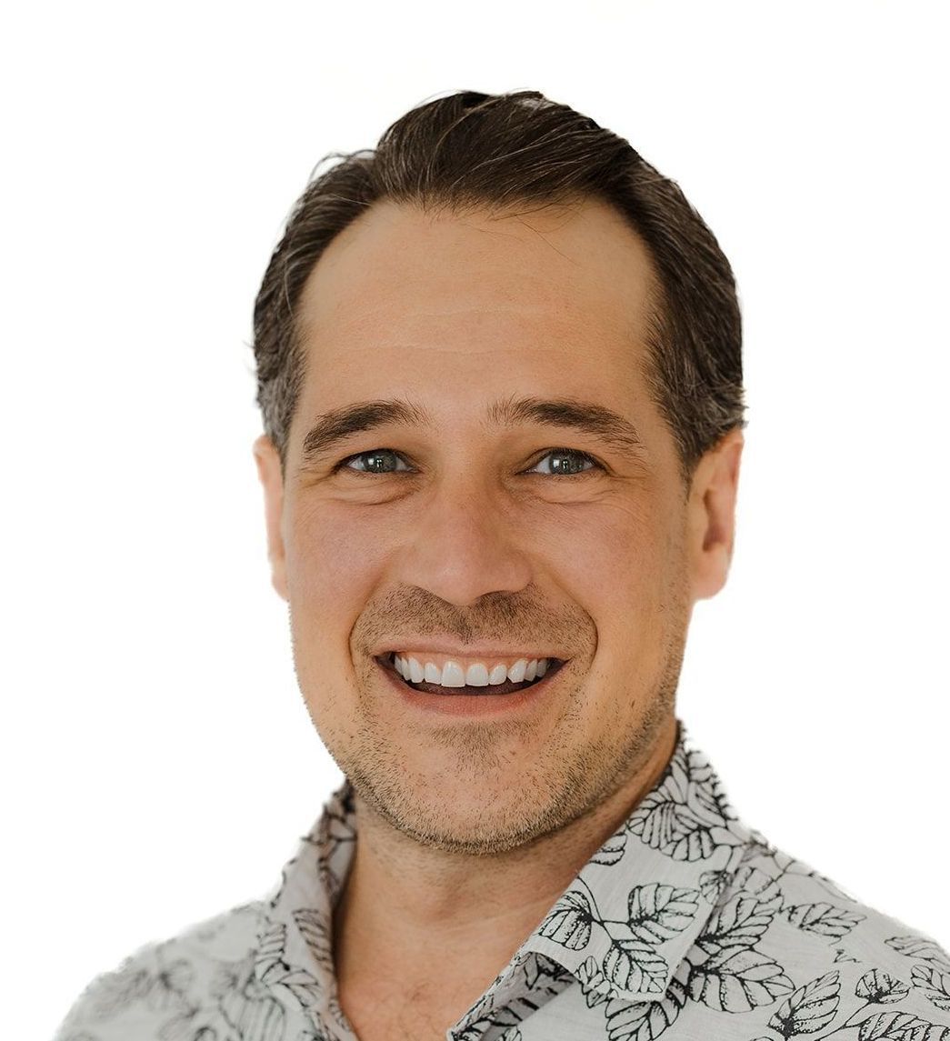 A man wearing a floral shirt is smiling for the camera.