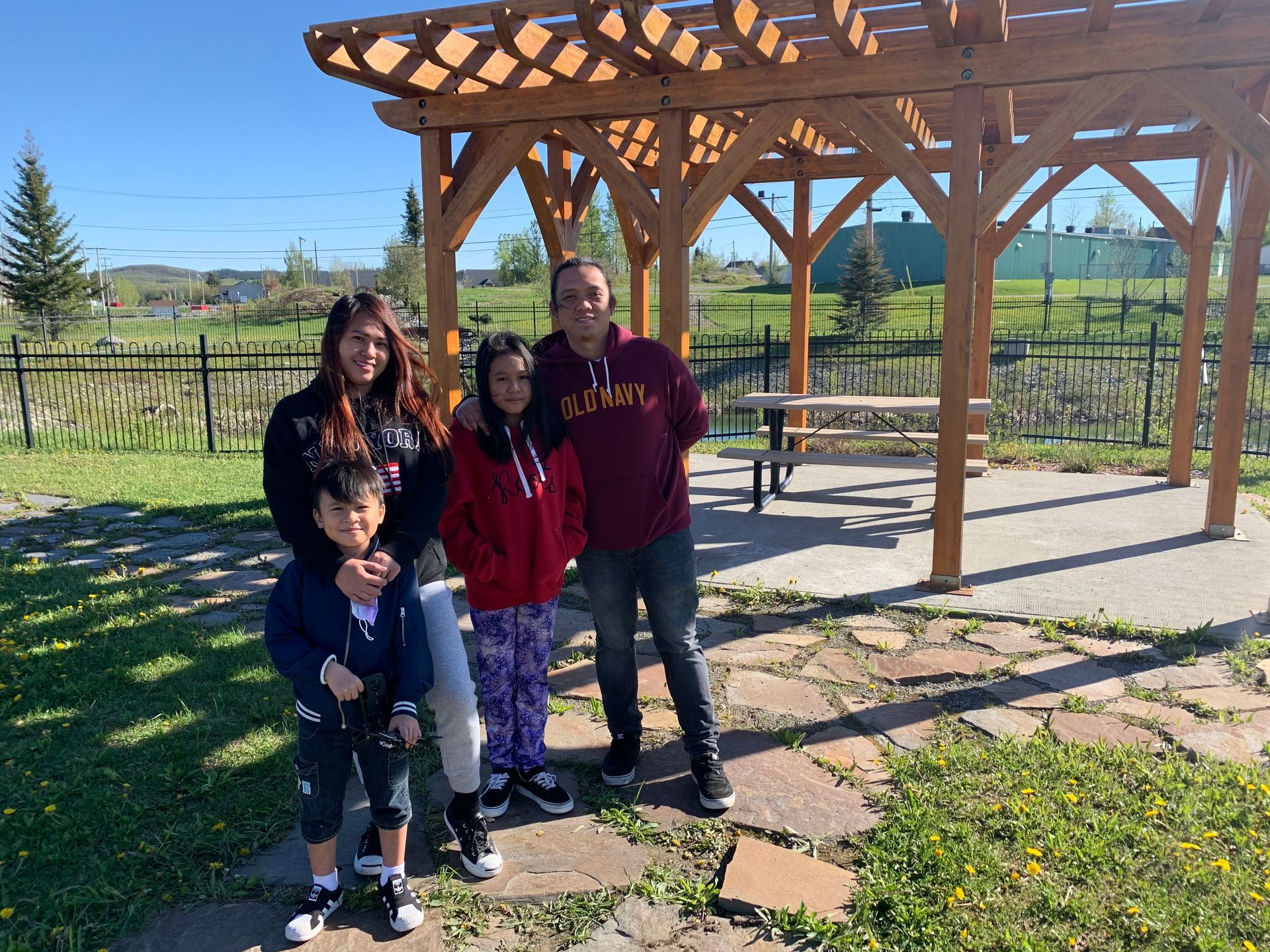 A family is posing for a picture in front of a wooden pergola.