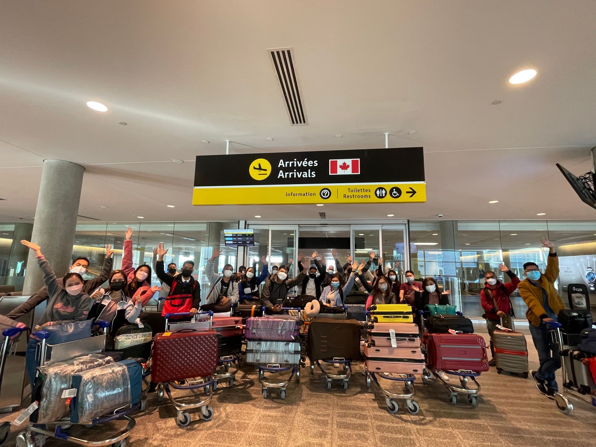 A group of people are standing in front of a sign that says arrivals arrivals.