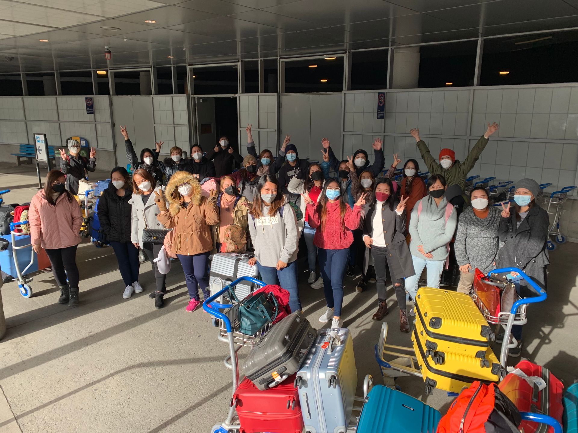 A group of people wearing masks are posing for a picture at an airport.