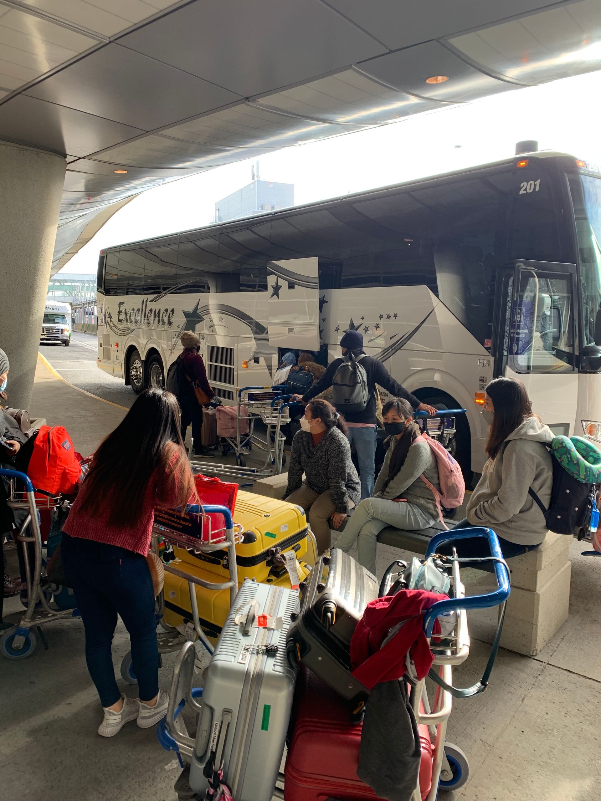 A group of people are waiting for a bus at an airport.