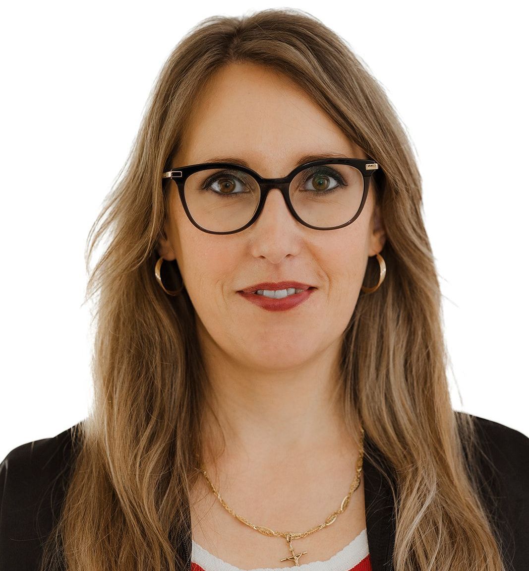 A woman wearing glasses and a necklace is smiling for the camera.