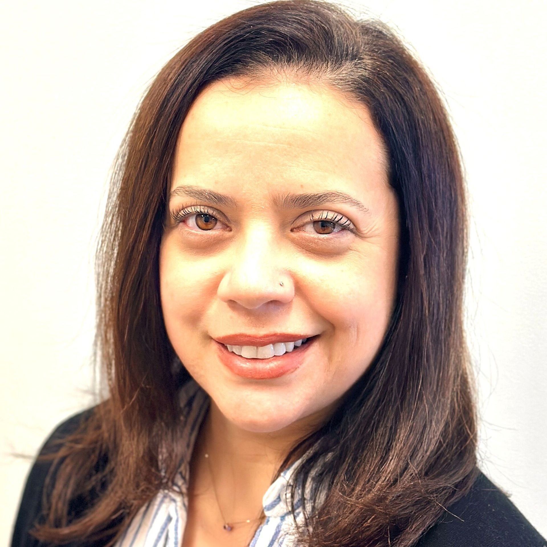 A woman with long brown hair is smiling for the camera.
