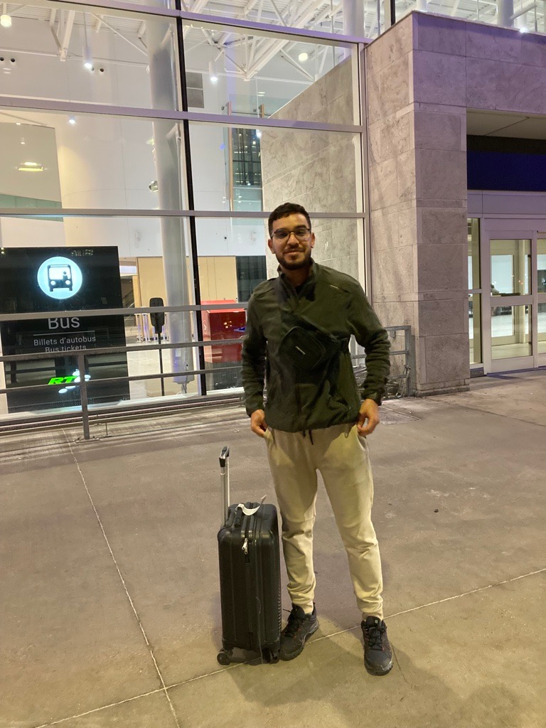 A man is standing next to a suitcase at an airport.