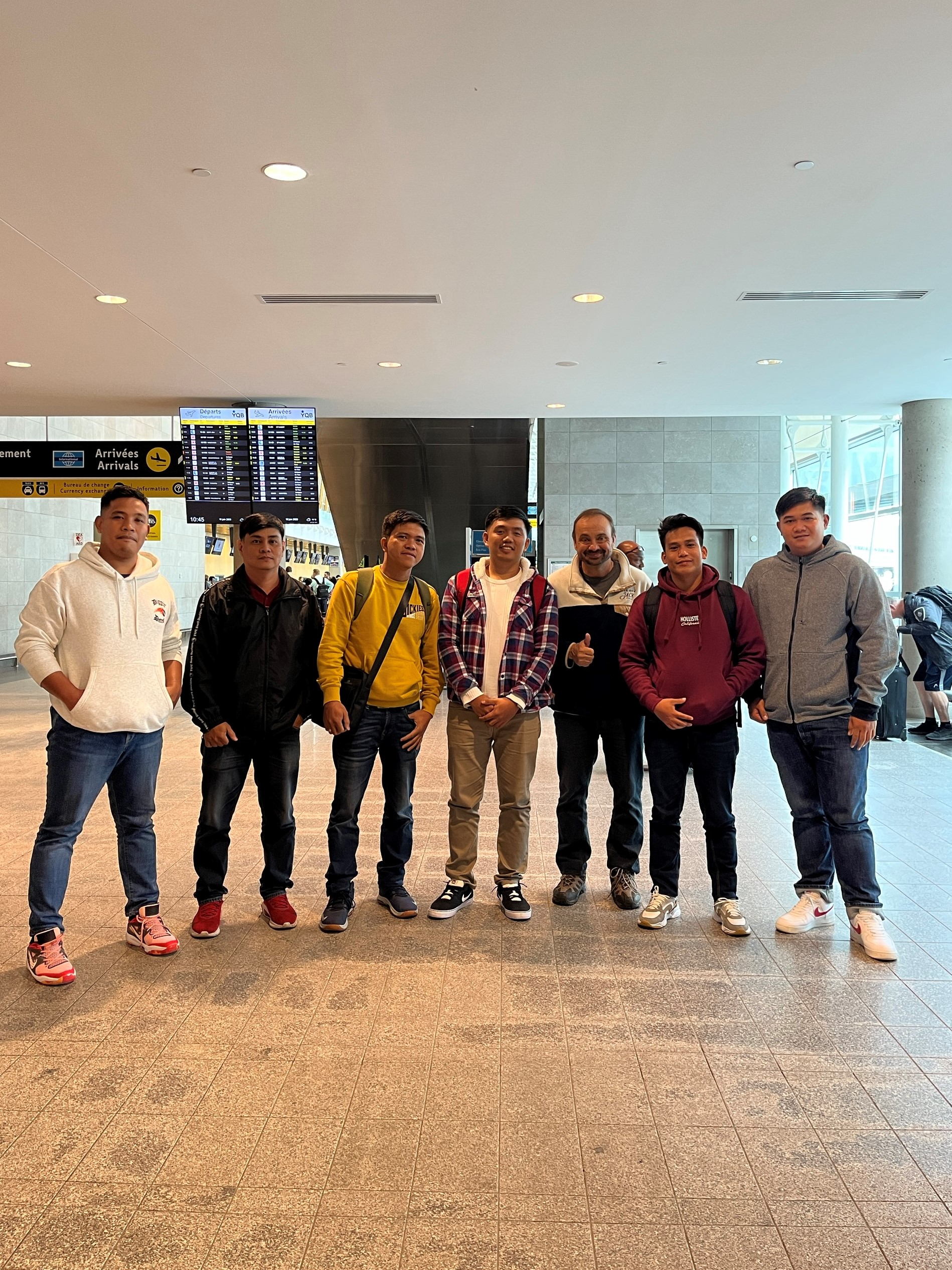 A group of young men are standing next to each other in an airport.