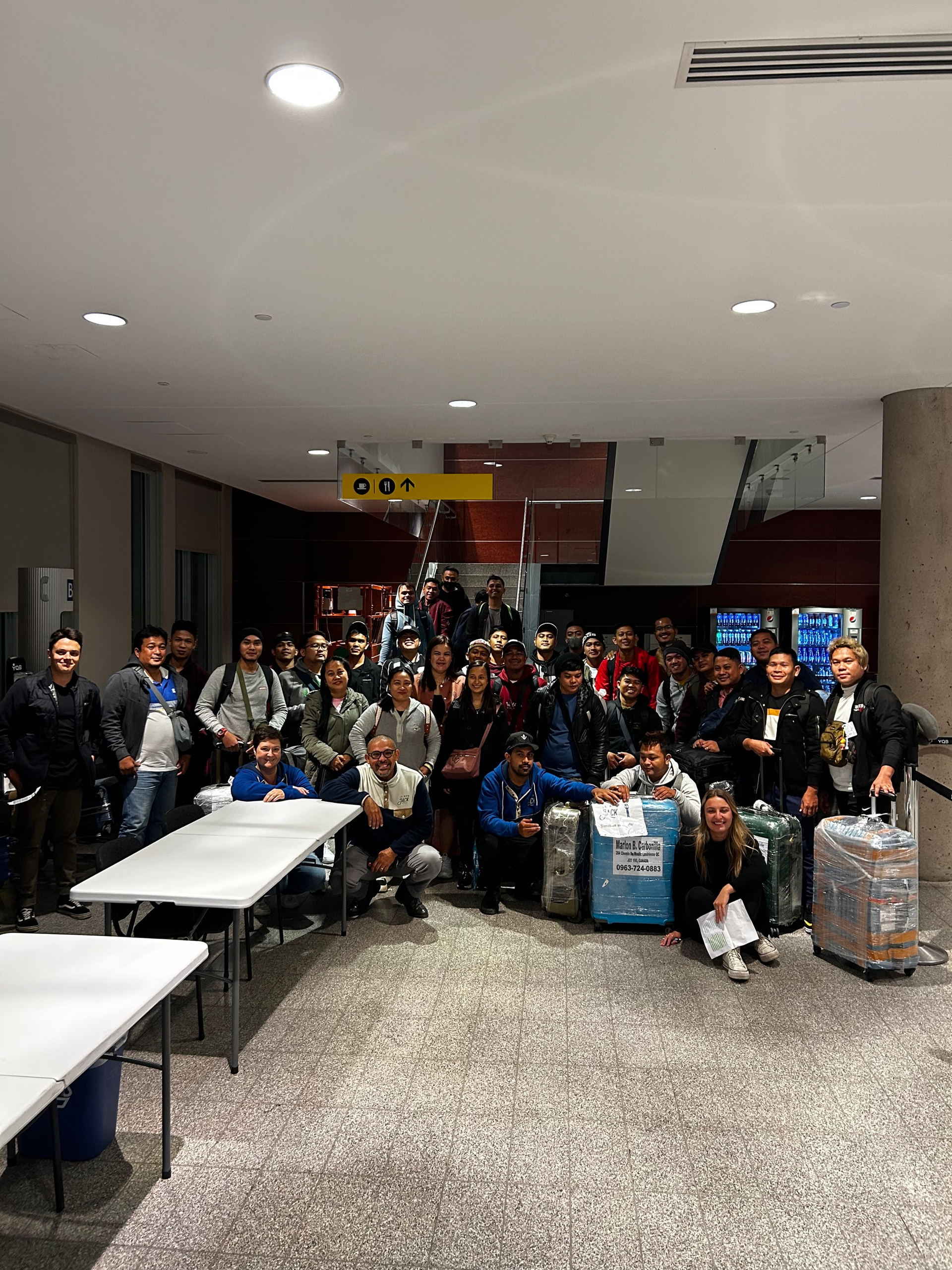 A group of people are posing for a picture in a room with luggage.