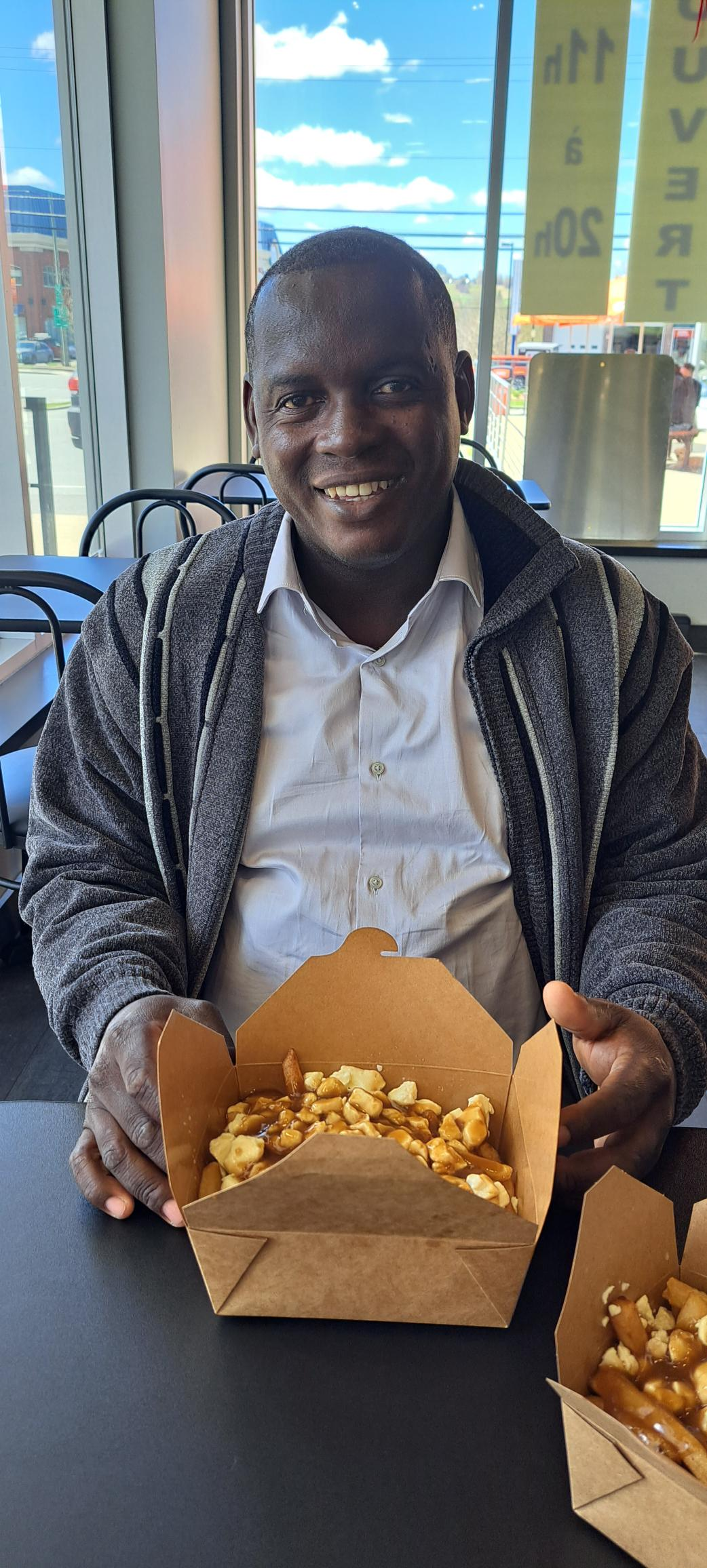 A man is sitting at a table holding a box of food.
