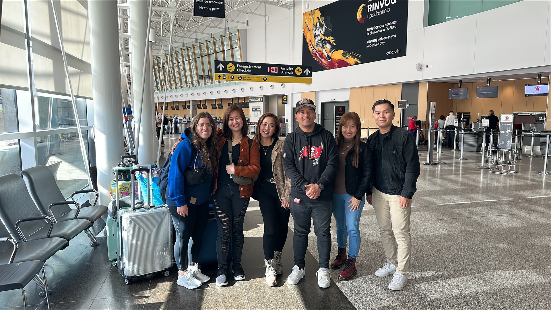 A group of people are posing for a picture at an airport.