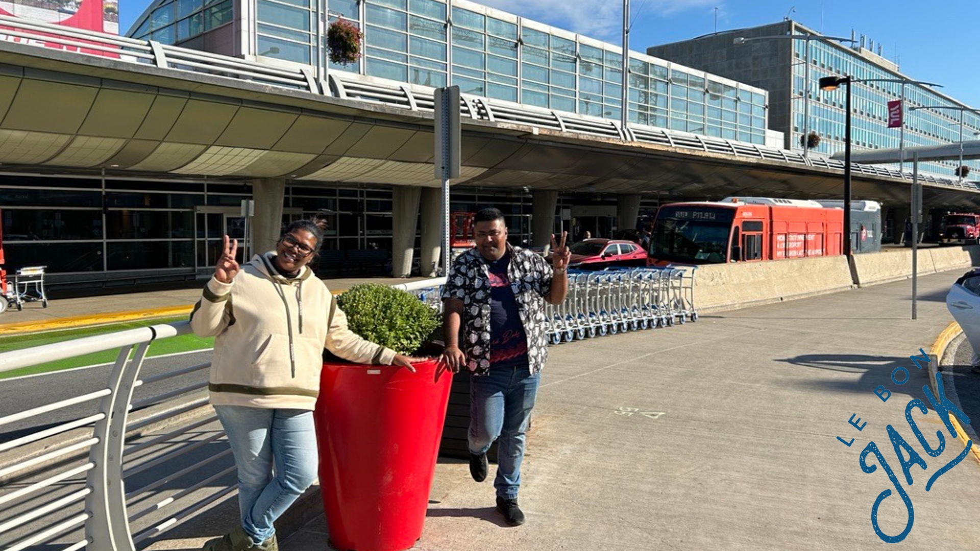 A man and a woman are standing next to each other in front of an airport.