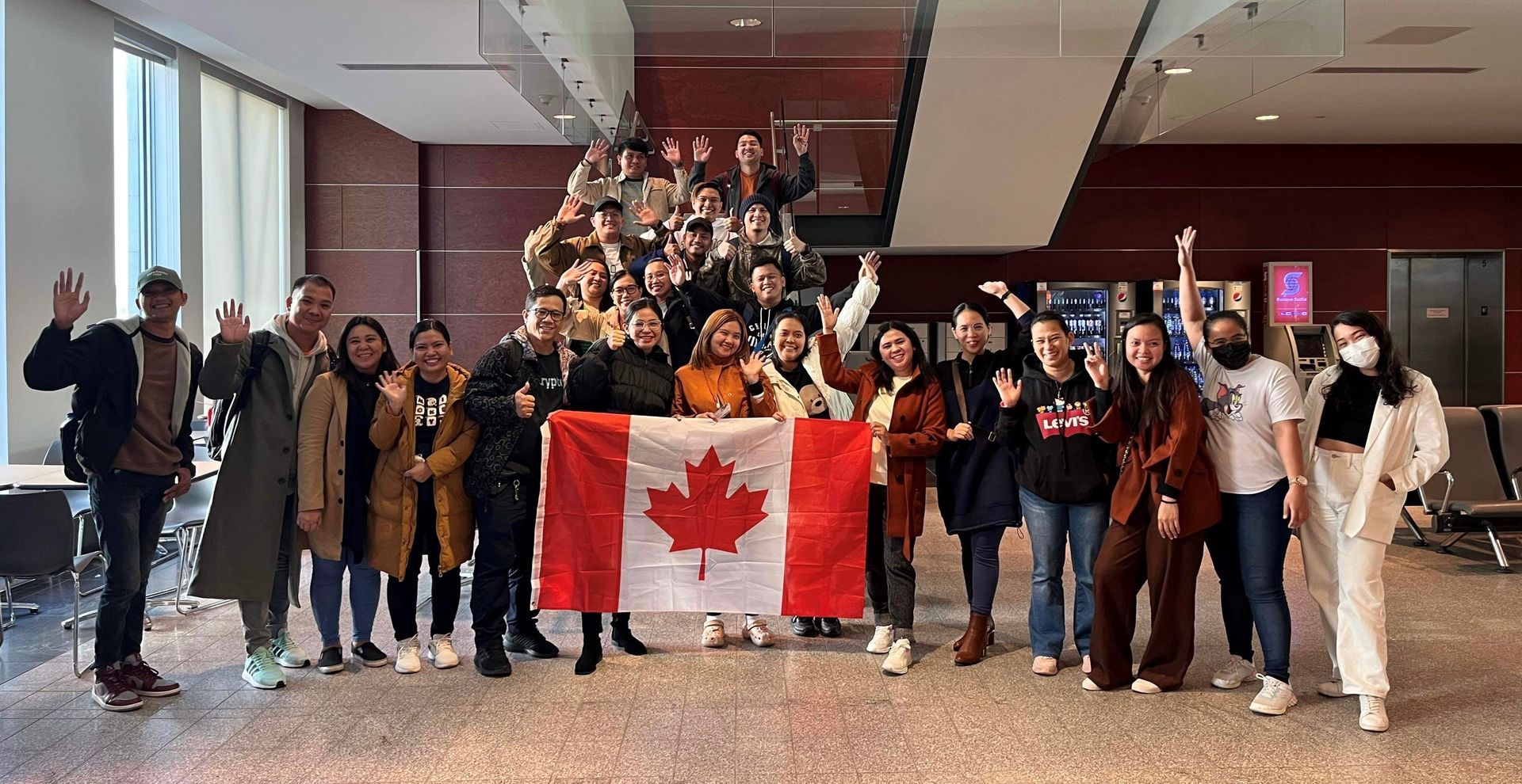 A group of people are posing for a picture while holding a canadian flag.