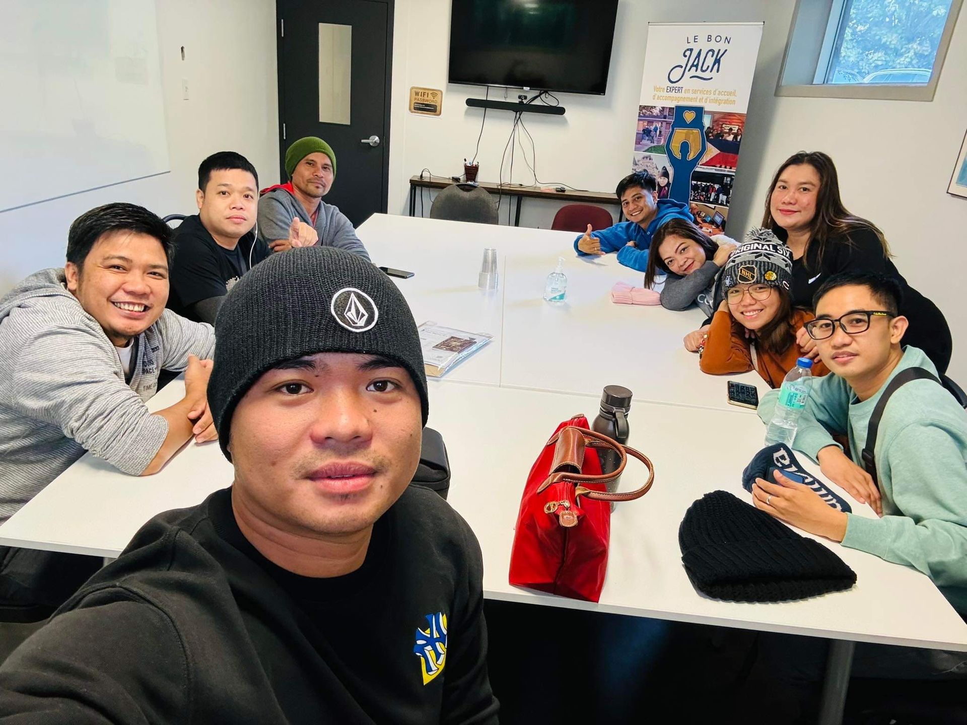 A man is taking a selfie with a group of people sitting around a table.