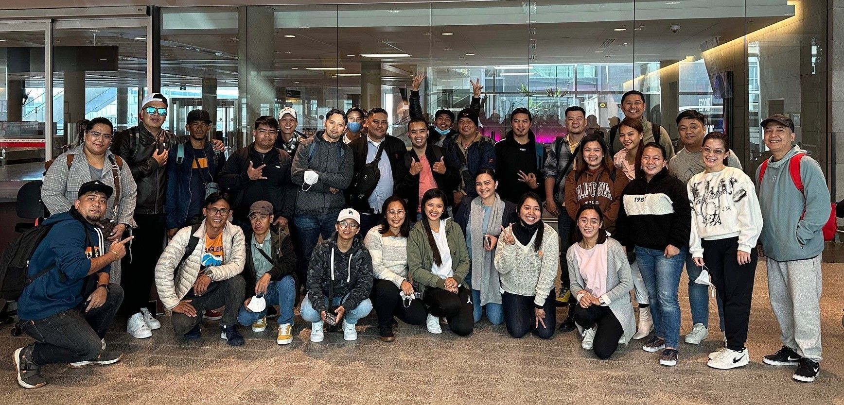 A large group of people are posing for a picture in an airport.