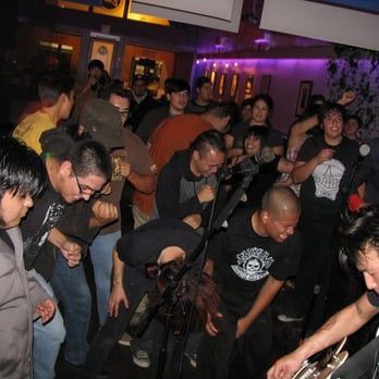 A crowd of people are gathered in a room with purple lights