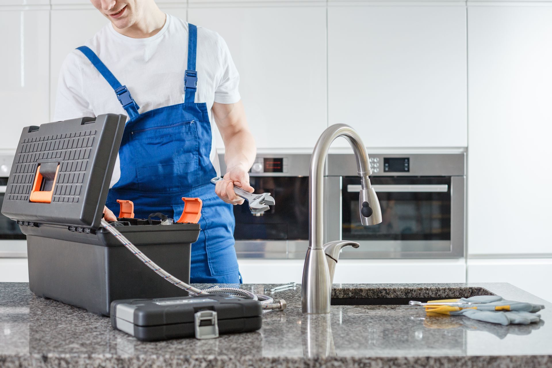 Plumber with wrench installing a new kitchen faucet