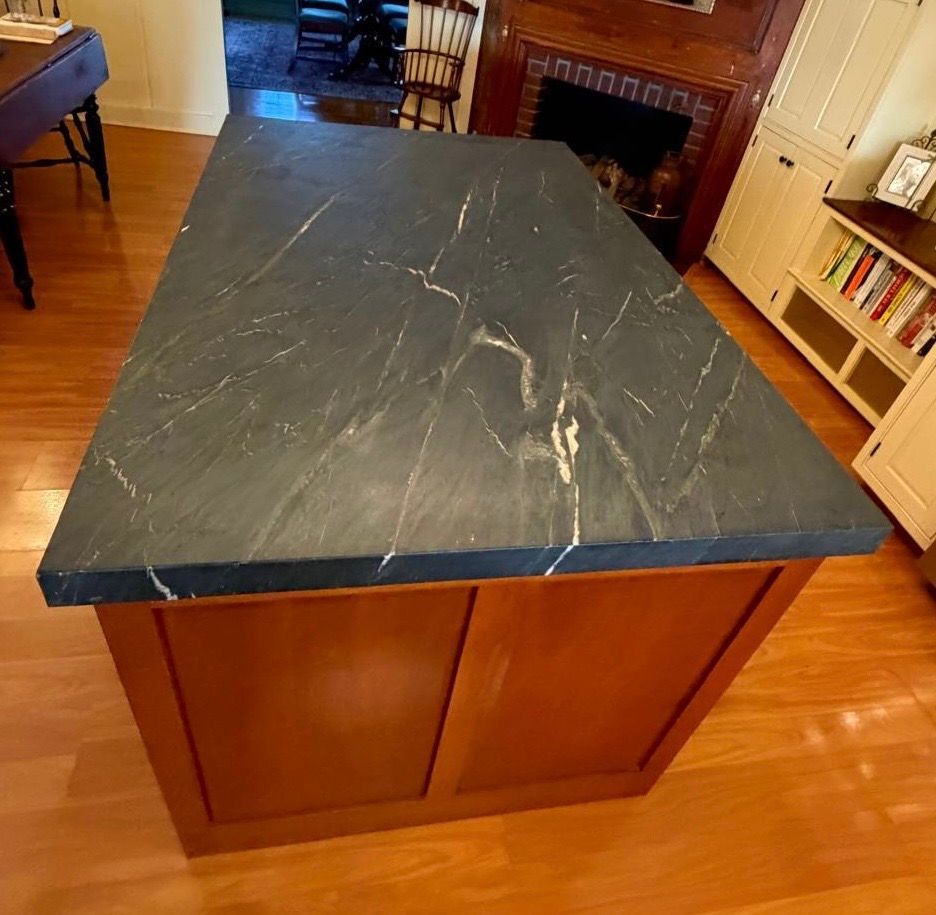 Kitchen island with a black marble-look countertop and wooden base in a home interior