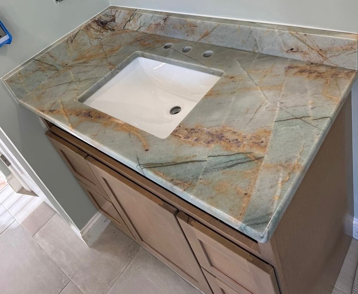 Bathroom vanity with a stone countertop and white square sink.