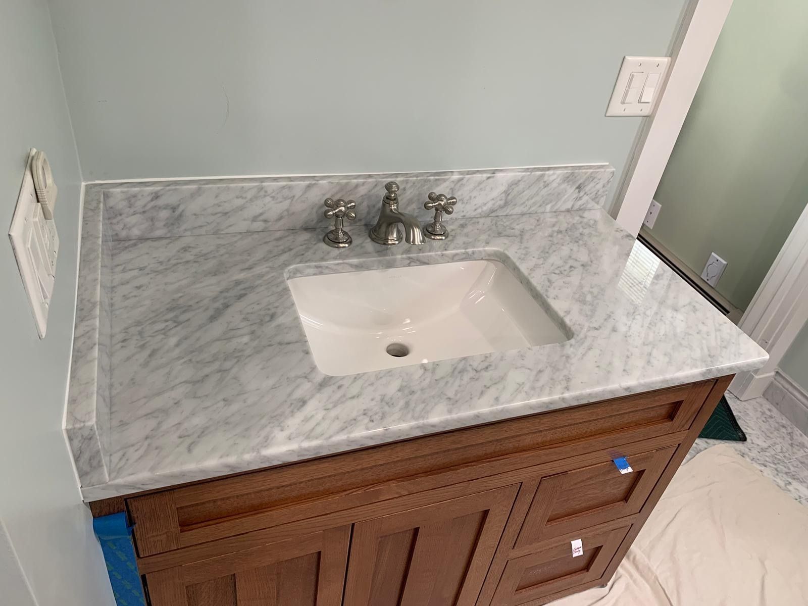 Bathroom vanity with white marble top, undermount sink, and wood cabinet drawers