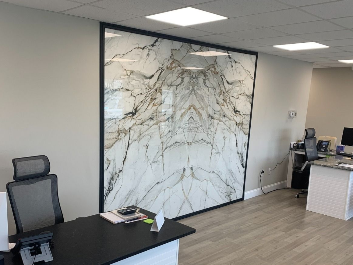 Modern office interior with desks, mesh chairs, and a large marble-pattern wall panel