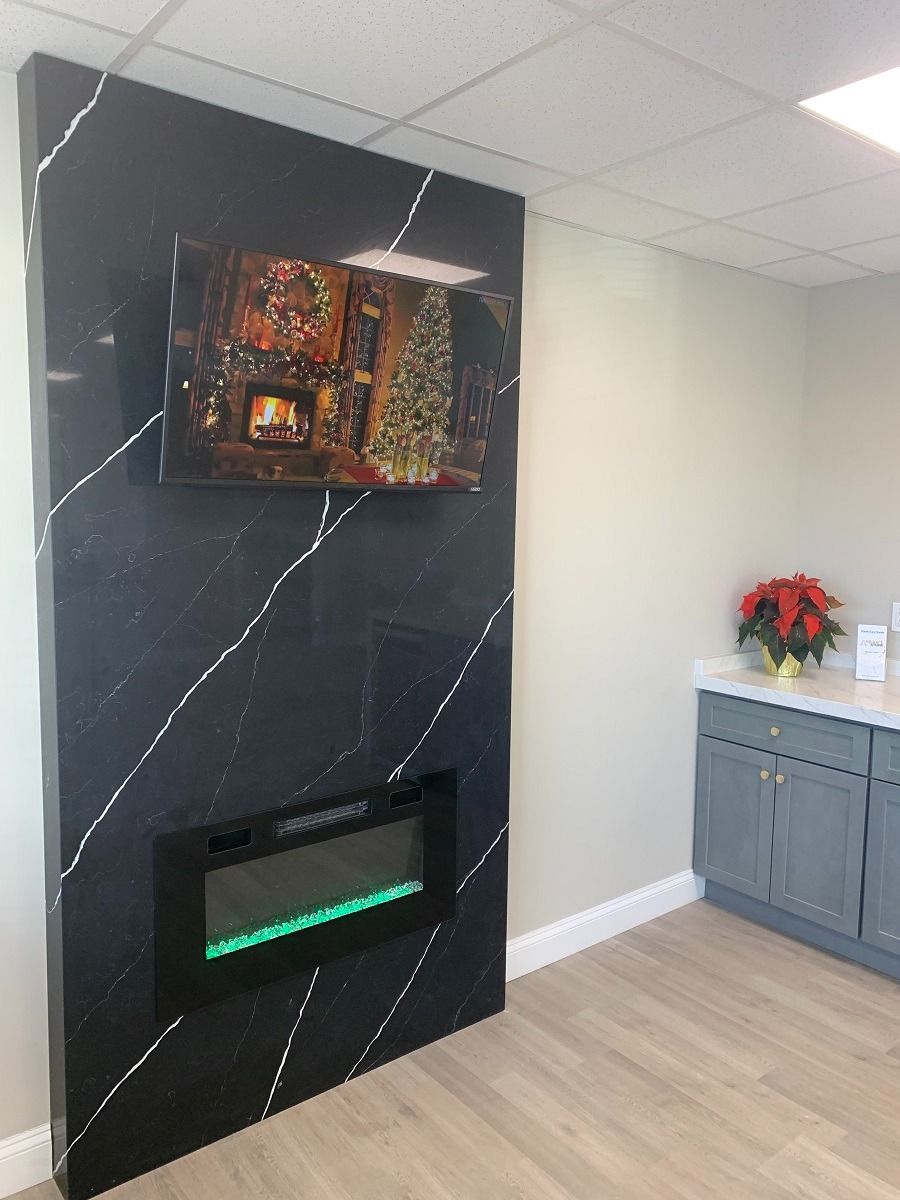 Stone fireplace with black hearth and mantel against a white wall, with fireplace tools inside