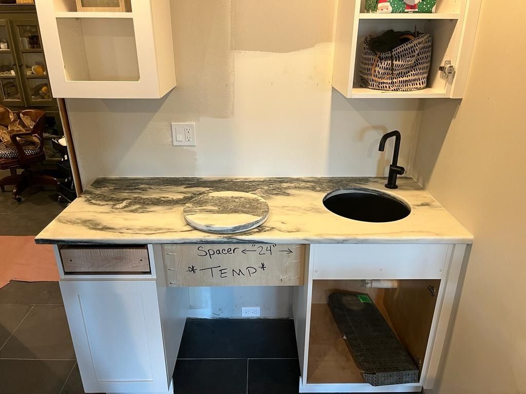 Partially renovated kitchen counter with sink, open cabinets, and dusty work surface