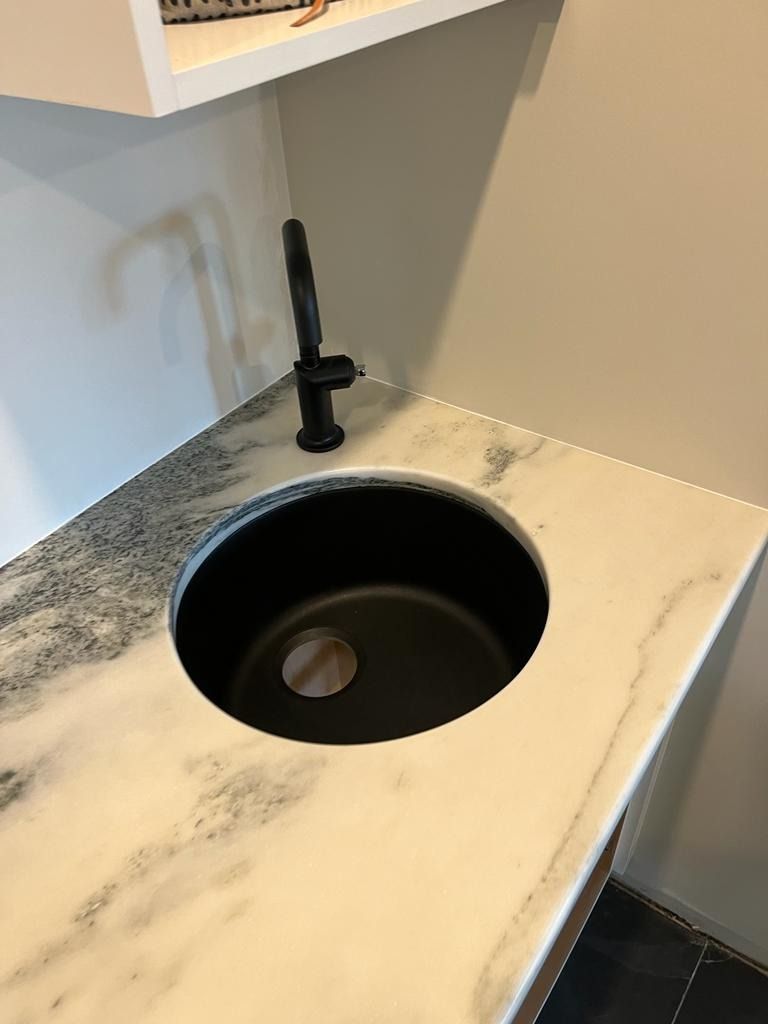 Modern countertop sink with black faucet and round basin in a compact room