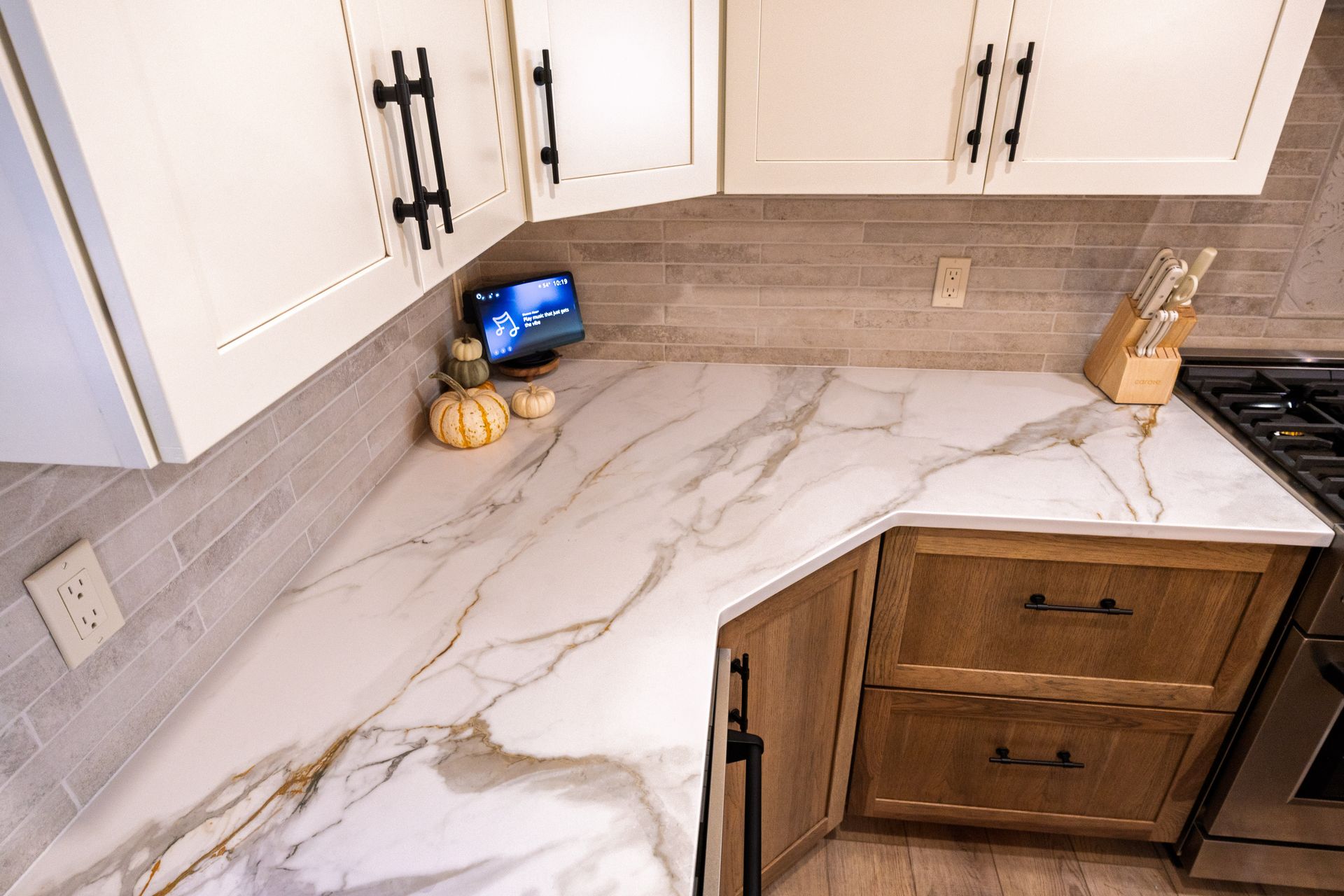 White marble-look kitchen countertop with white cabinets and a small tablet on the back corner