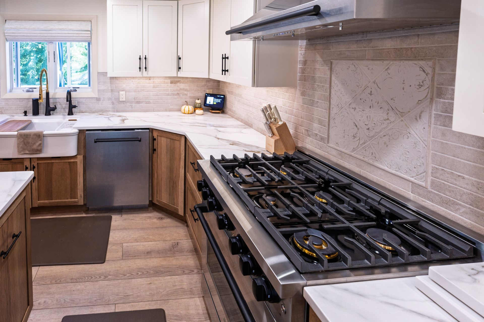 Modern kitchen with gas stove, white cabinets, stainless dishwasher, and window over the sink