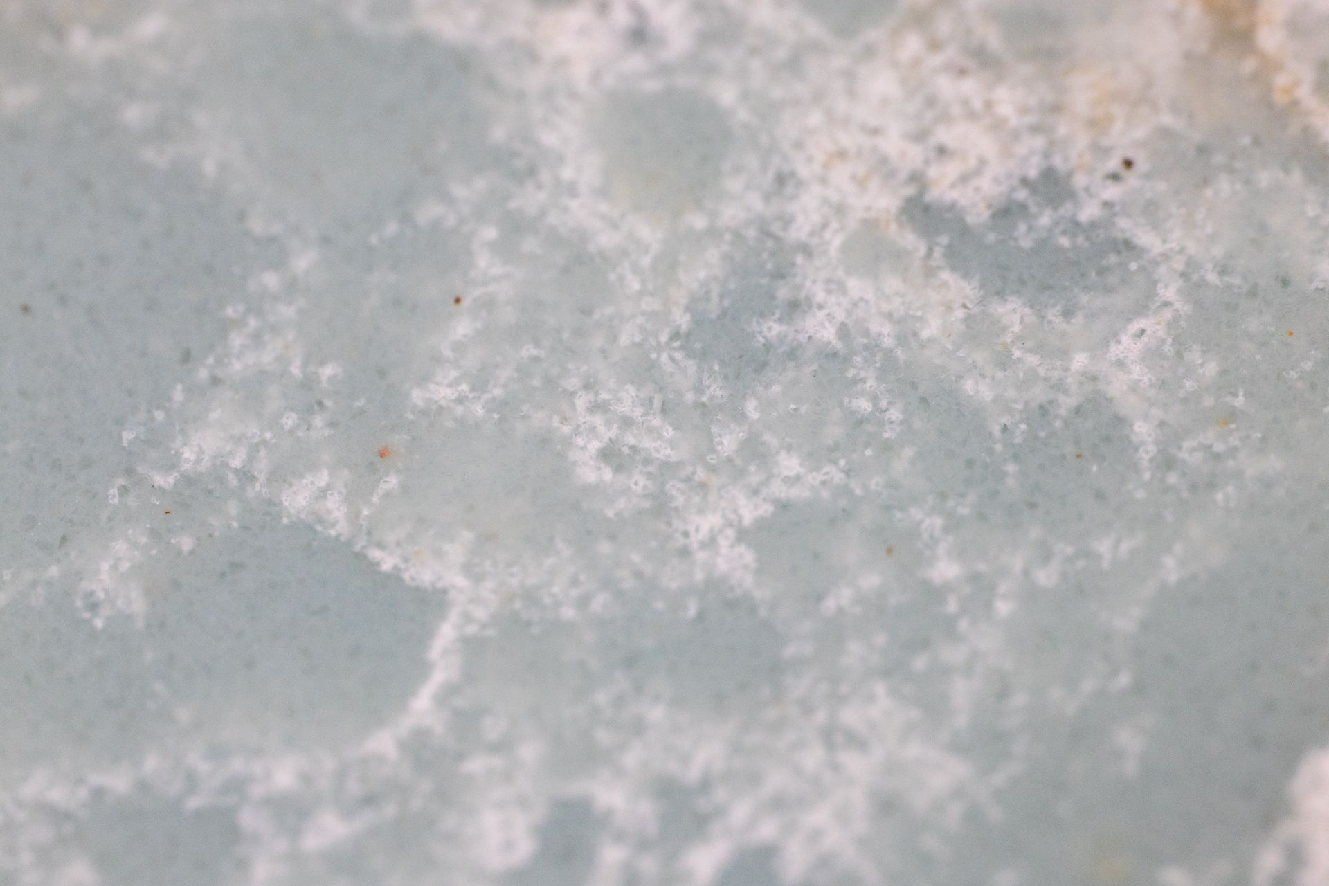 Pale gray stone surface with white cloudy patches and a rough, speckled pattern