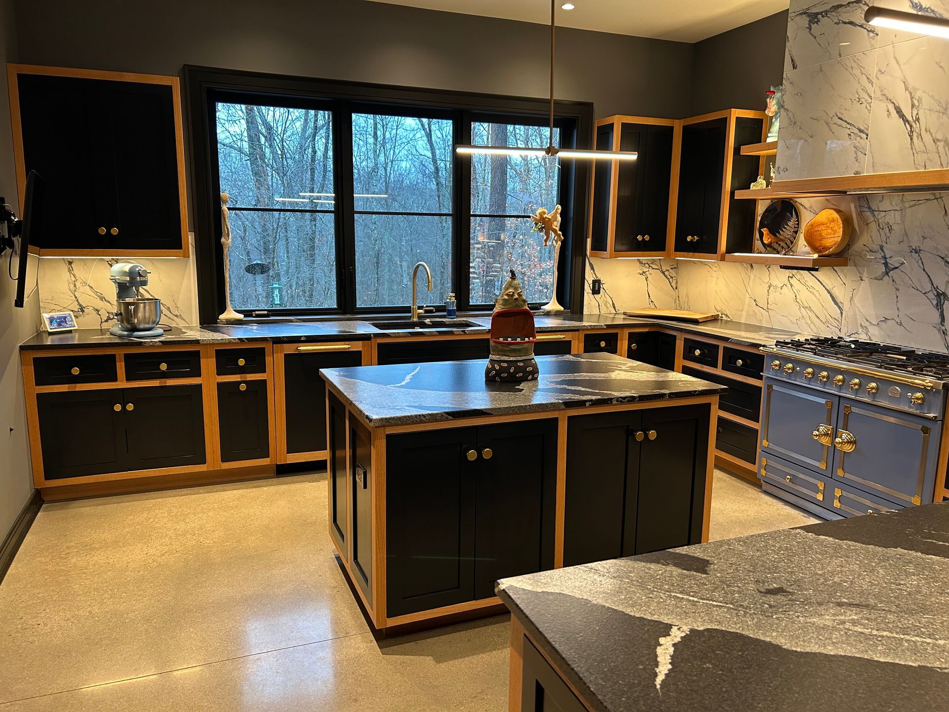 Partially renovated kitchen with dark cabinets, black countertops, and a large window over the sink.