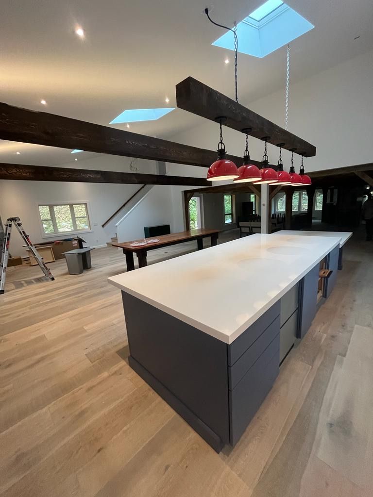 Modern kitchen with a large island, pendant lights, skylights, and exposed wood beams