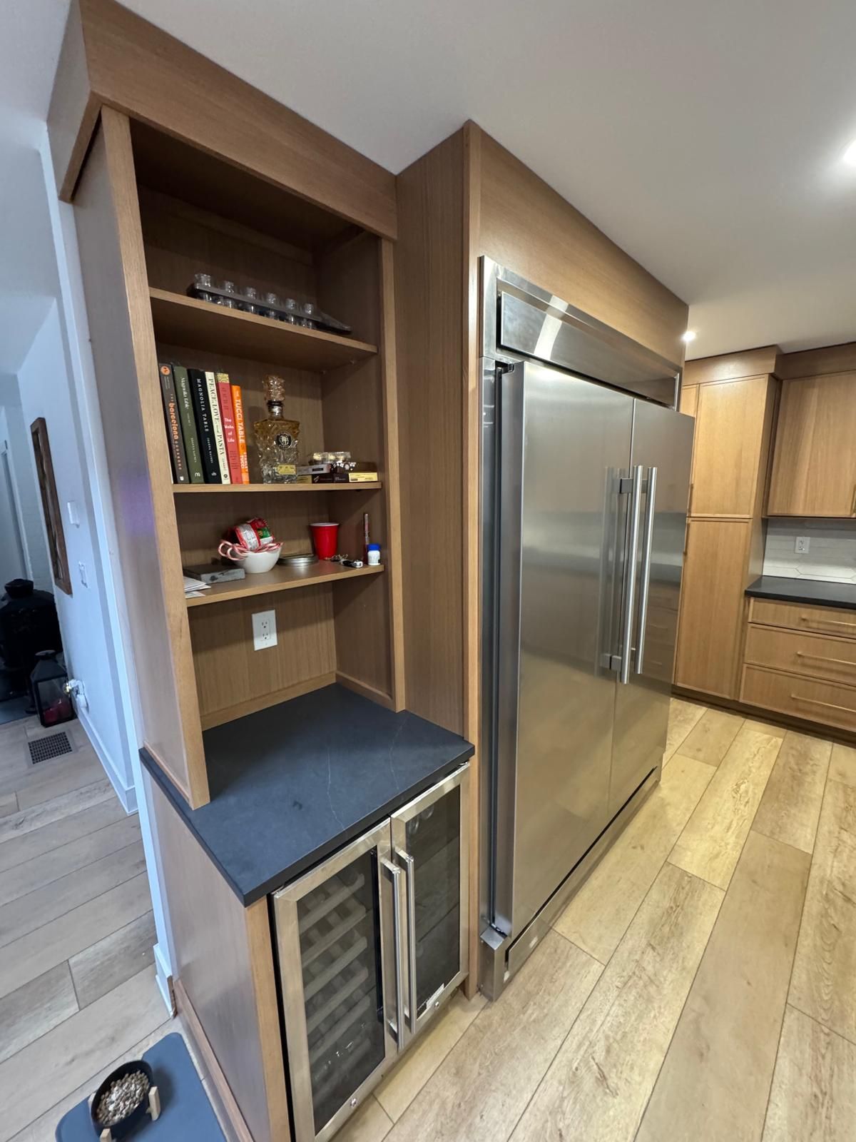 Modern kitchen with stainless steel refrigerator and built-in bookshelf by a narrow counter