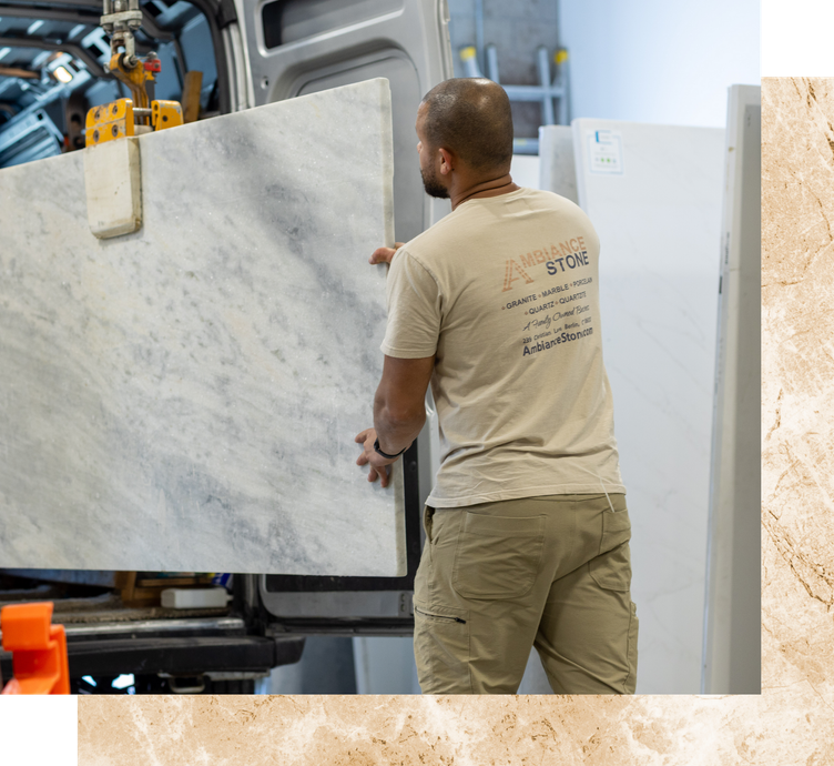 Worker loading a large white marble slab onto a machine in a warehouse