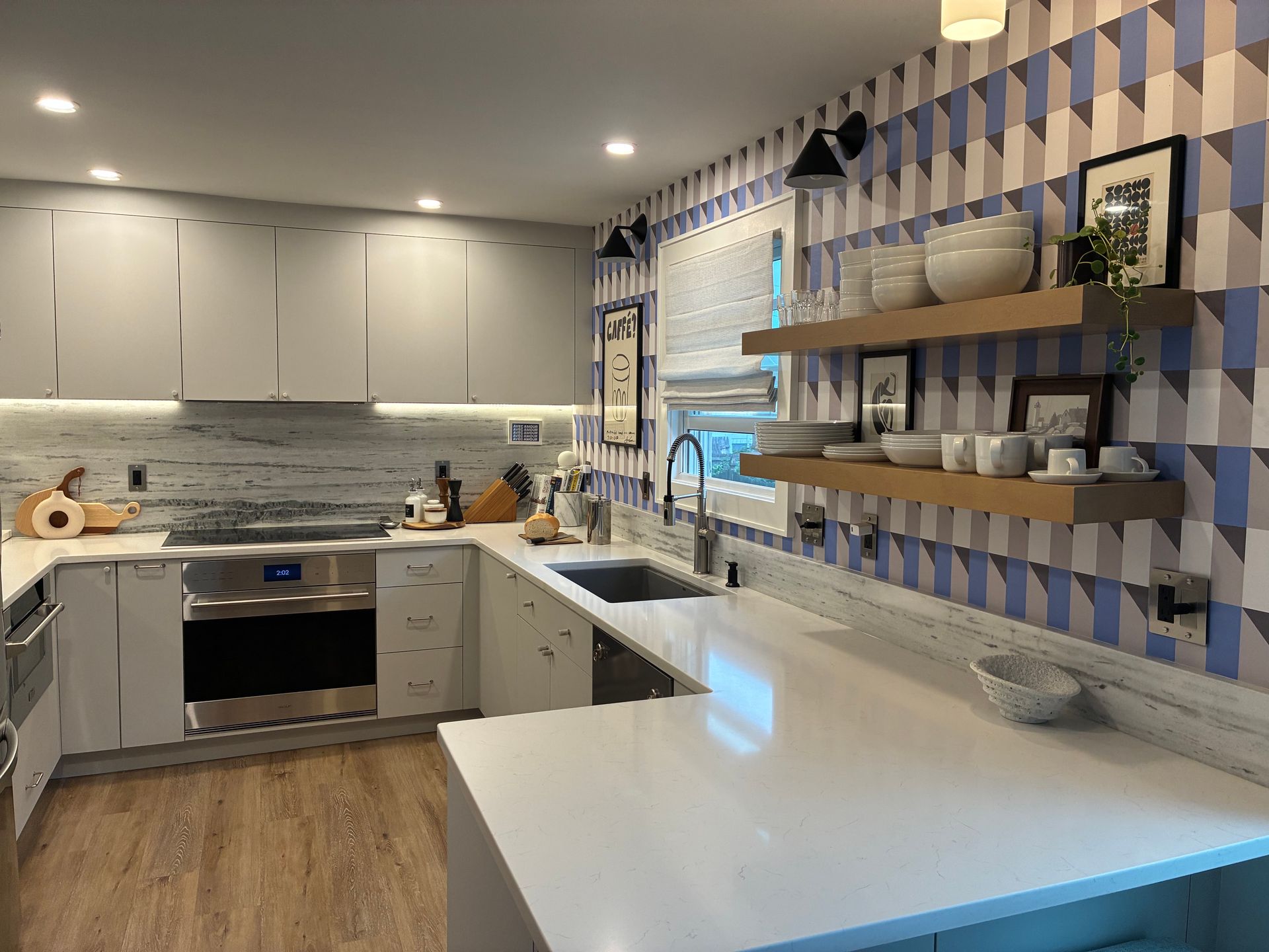 Bright modern kitchen with white cabinets, wood floor, blue-and-white tile wall, and a large white island.