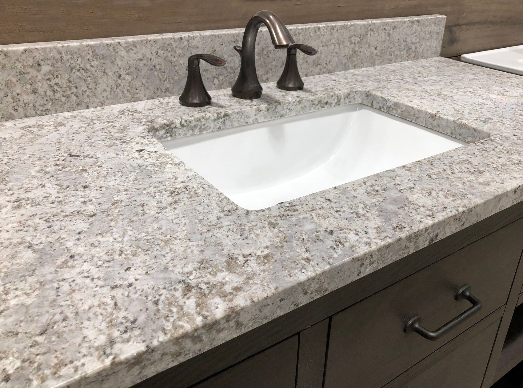 Granite bathroom vanity with white sink and dark bronze faucet fixtures