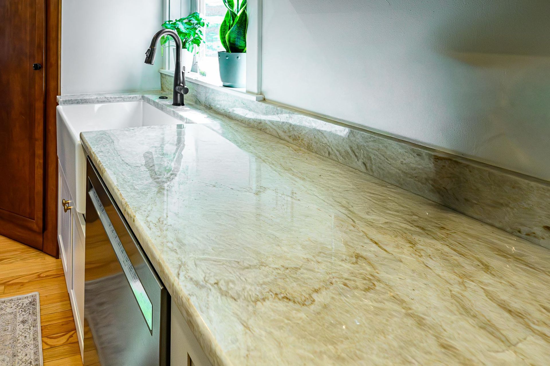 Granite kitchen countertop with sink, faucet, and potted plant by a window