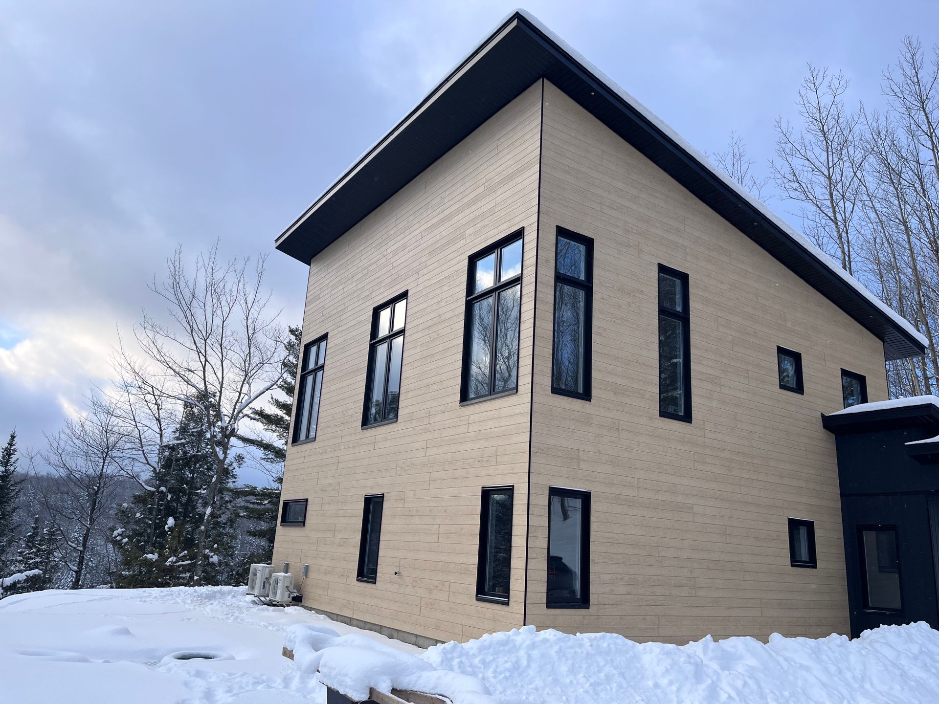 Une maison avec beaucoup de fenêtres est couverte de neige.