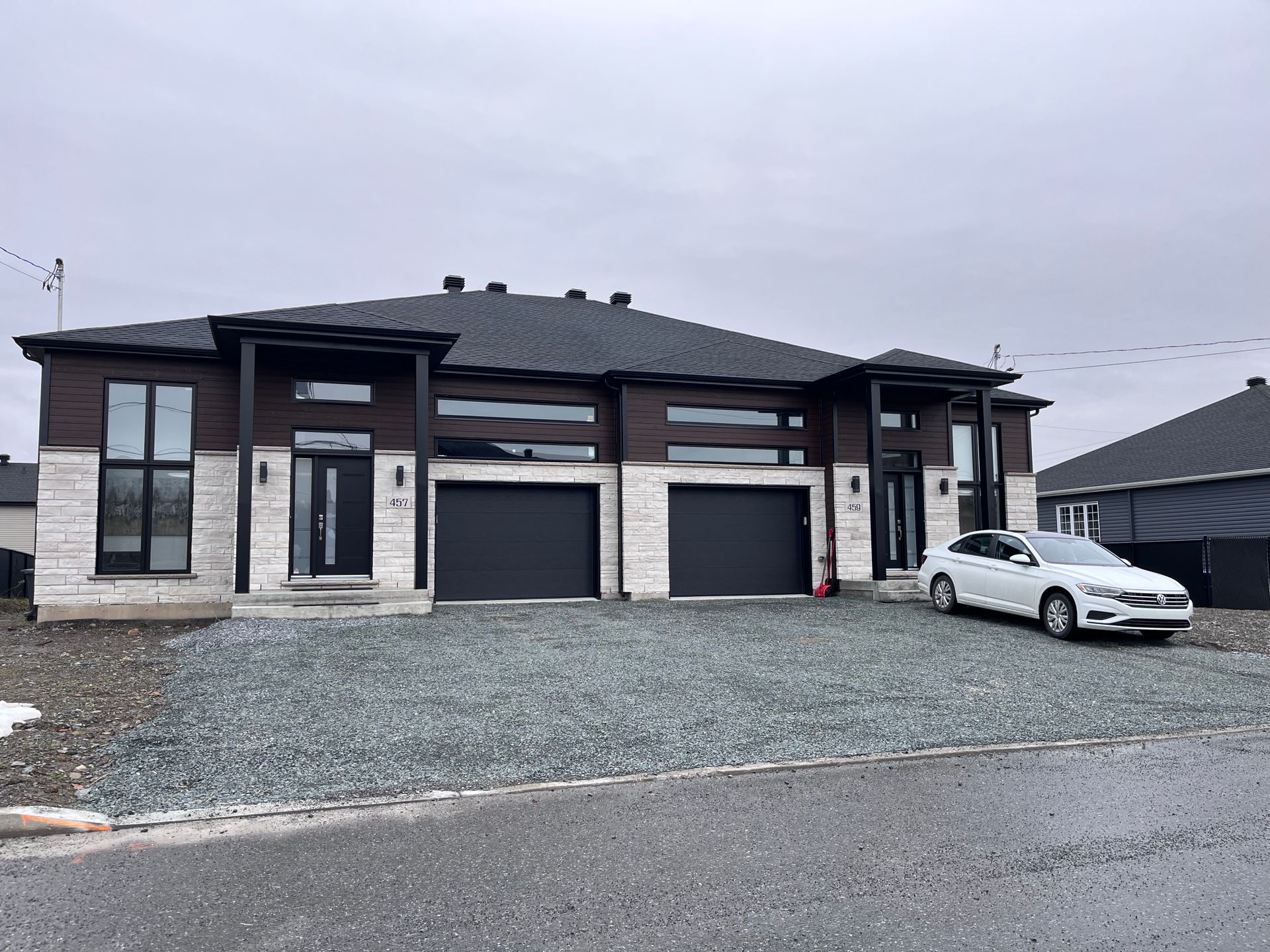 Une voiture blanche est garée devant une grande maison.