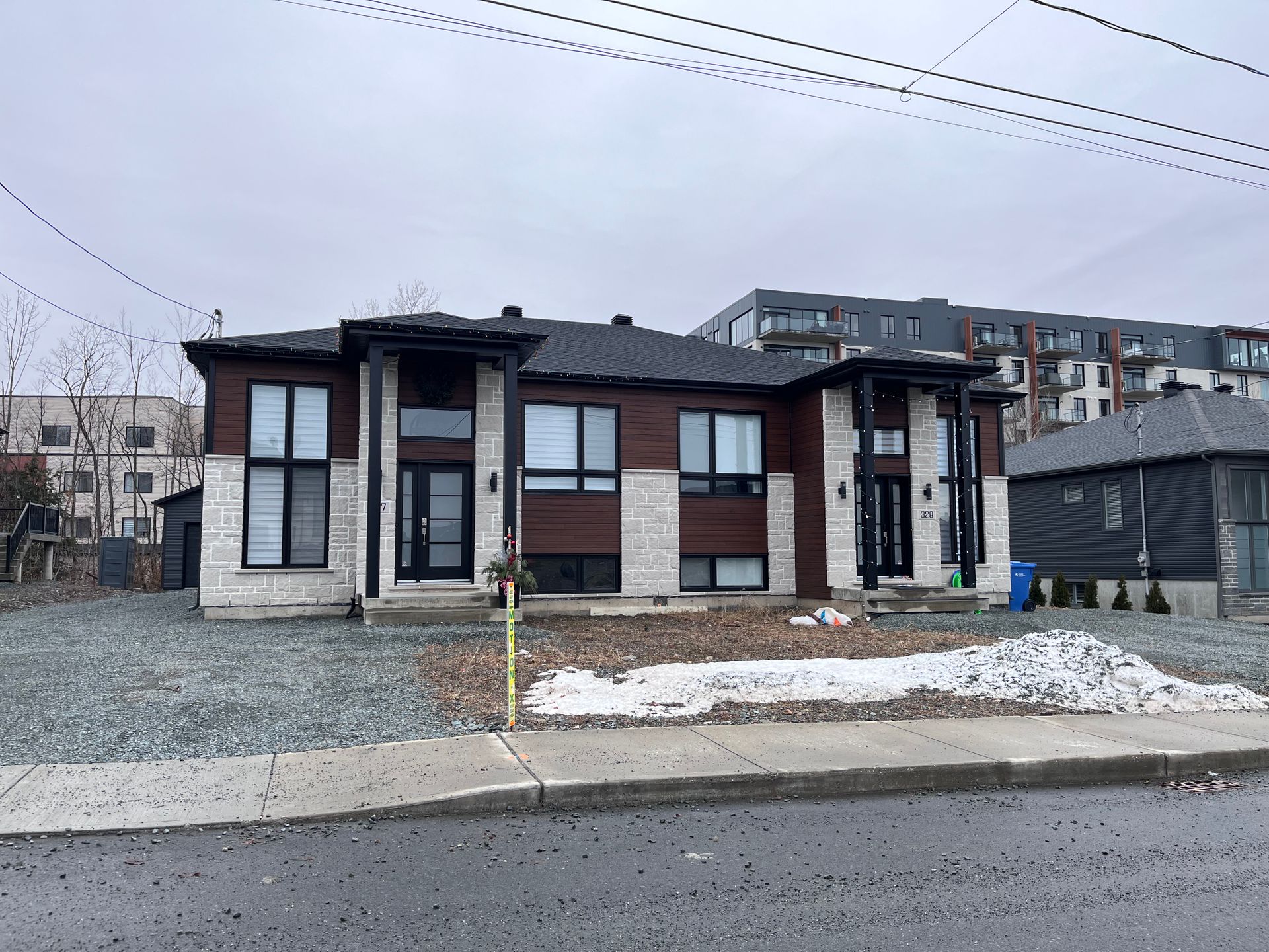 Une grande maison avec beaucoup de fenêtres se trouve au bord de la route.