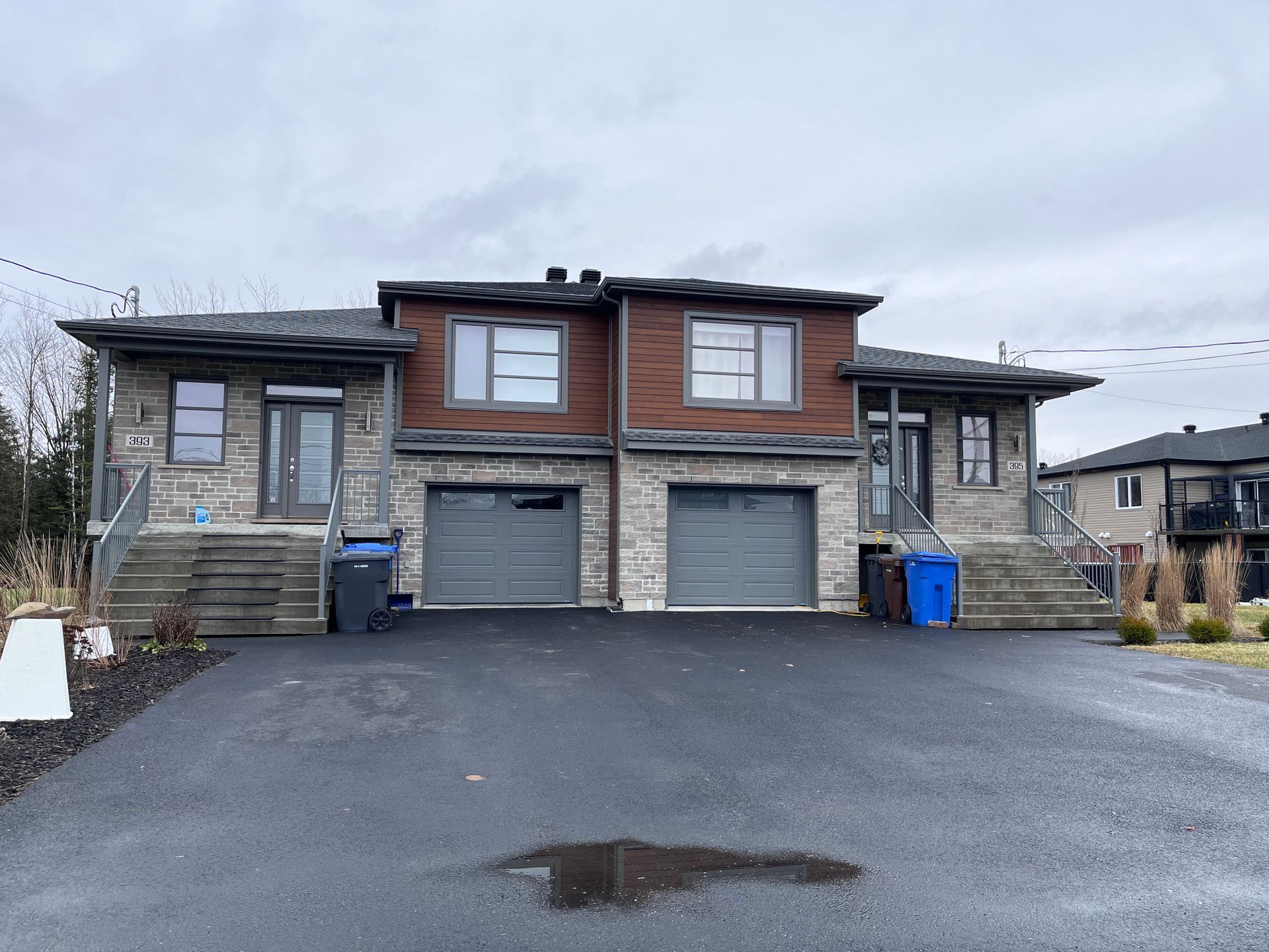 Une maison avec deux garages et une allée devant.
