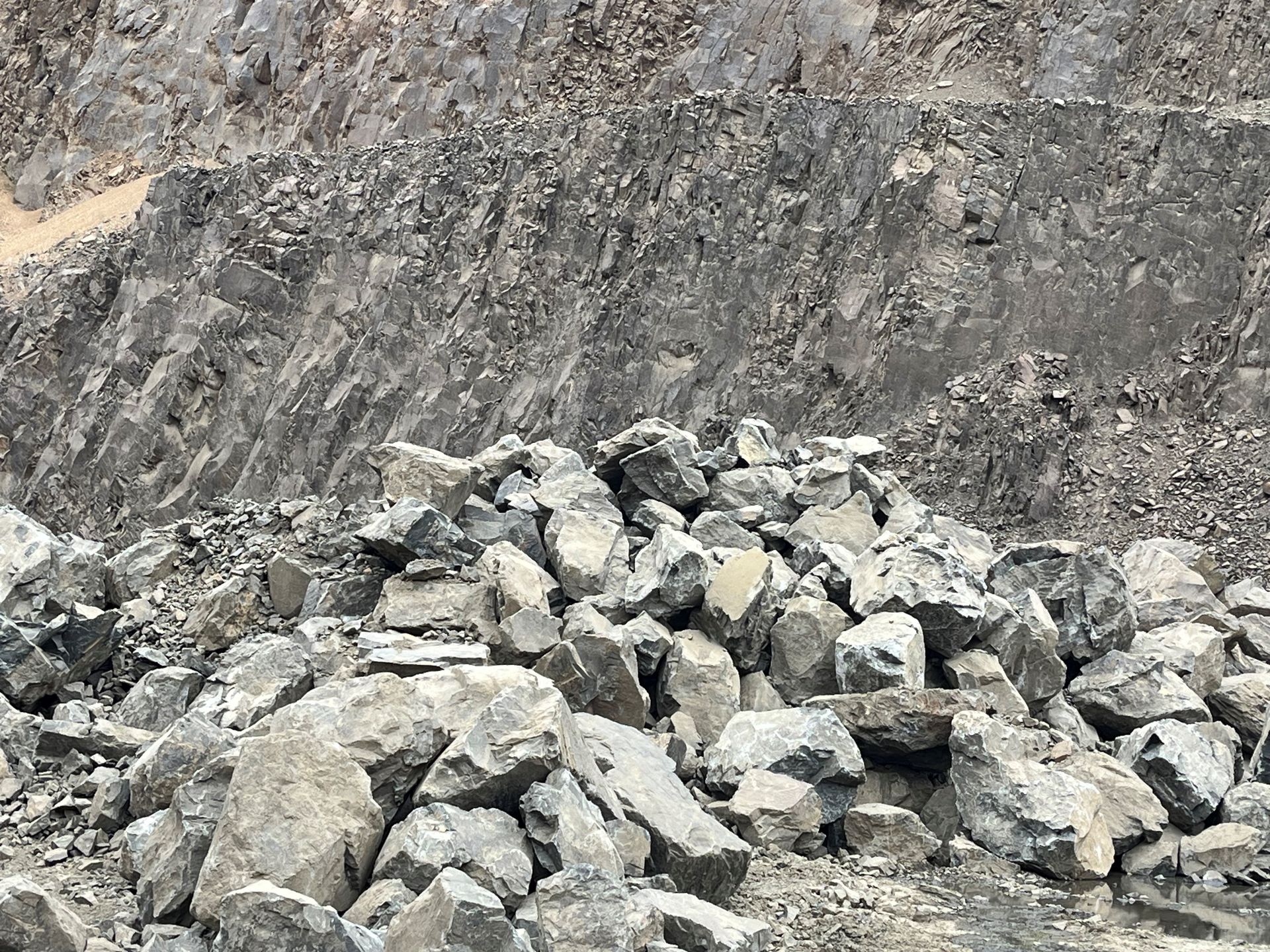 A large rock is sitting on top of a sandy hill.