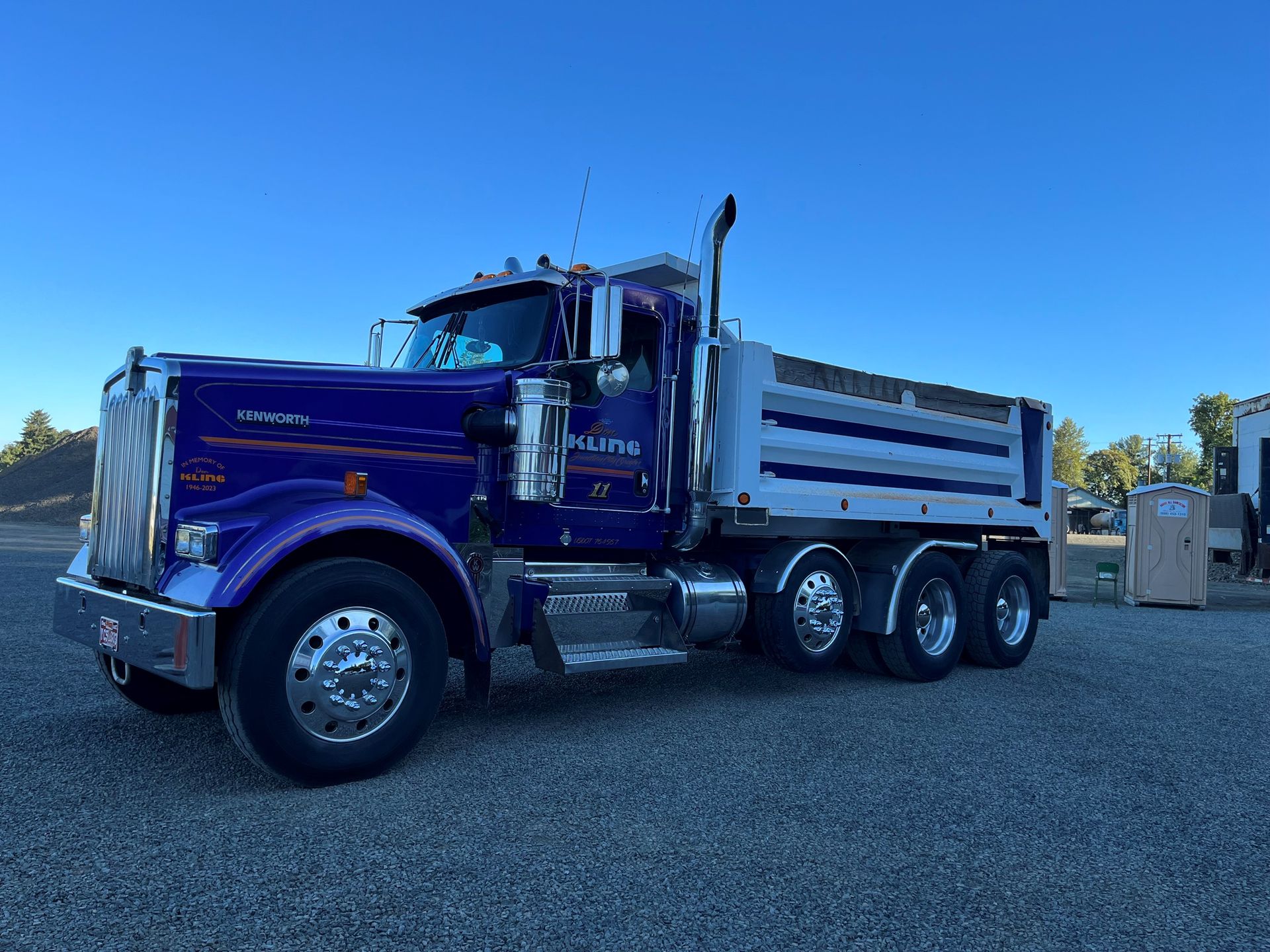A blue dump truck is parked in a gravel lot. A blue dump truck is parked in a gravel lot.
