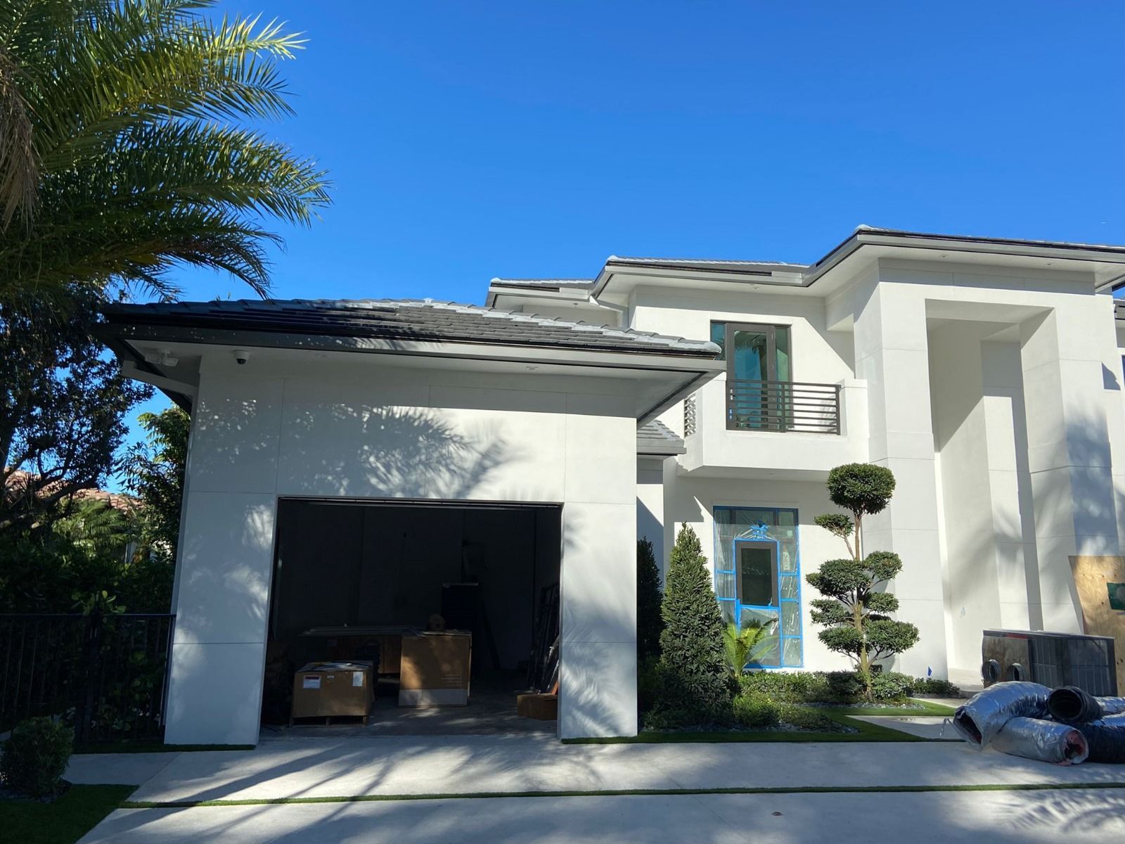 A white house with a garage and a blue sky in the background.