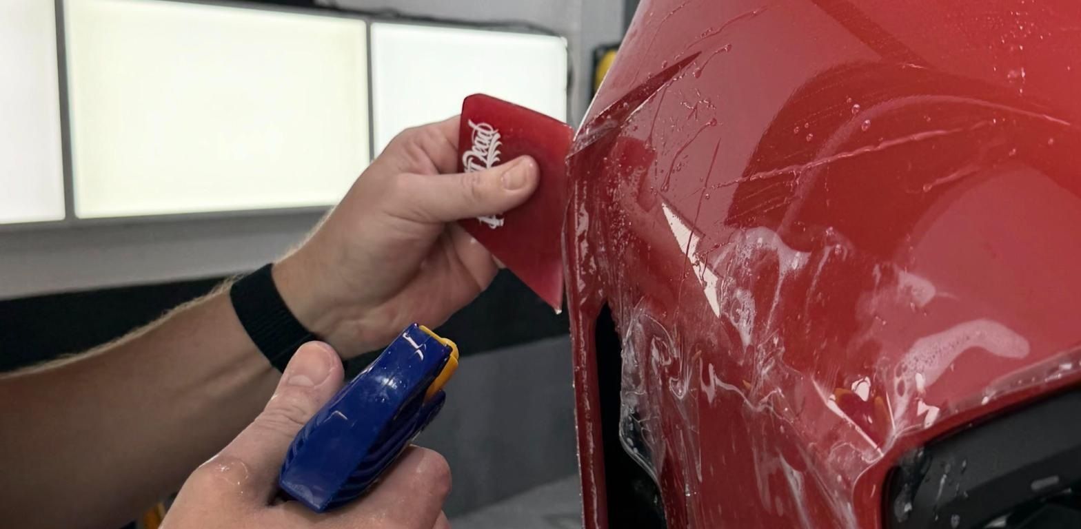 PWP Detailing technician installing LLumar paint protection film on a red Honda Civic Si bumper
