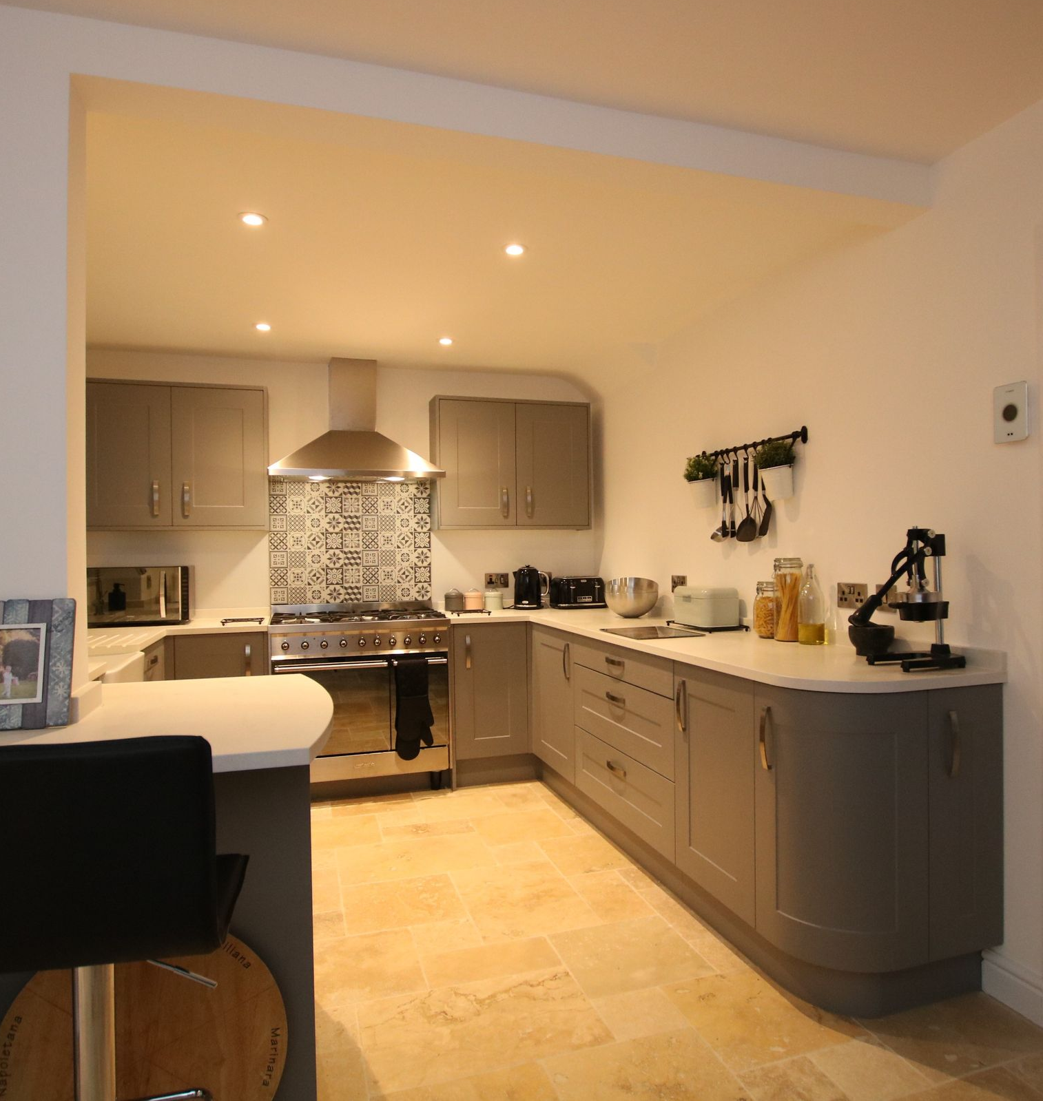 A kitchen with gray cabinets, stainless steel appliances, and beige flooring.